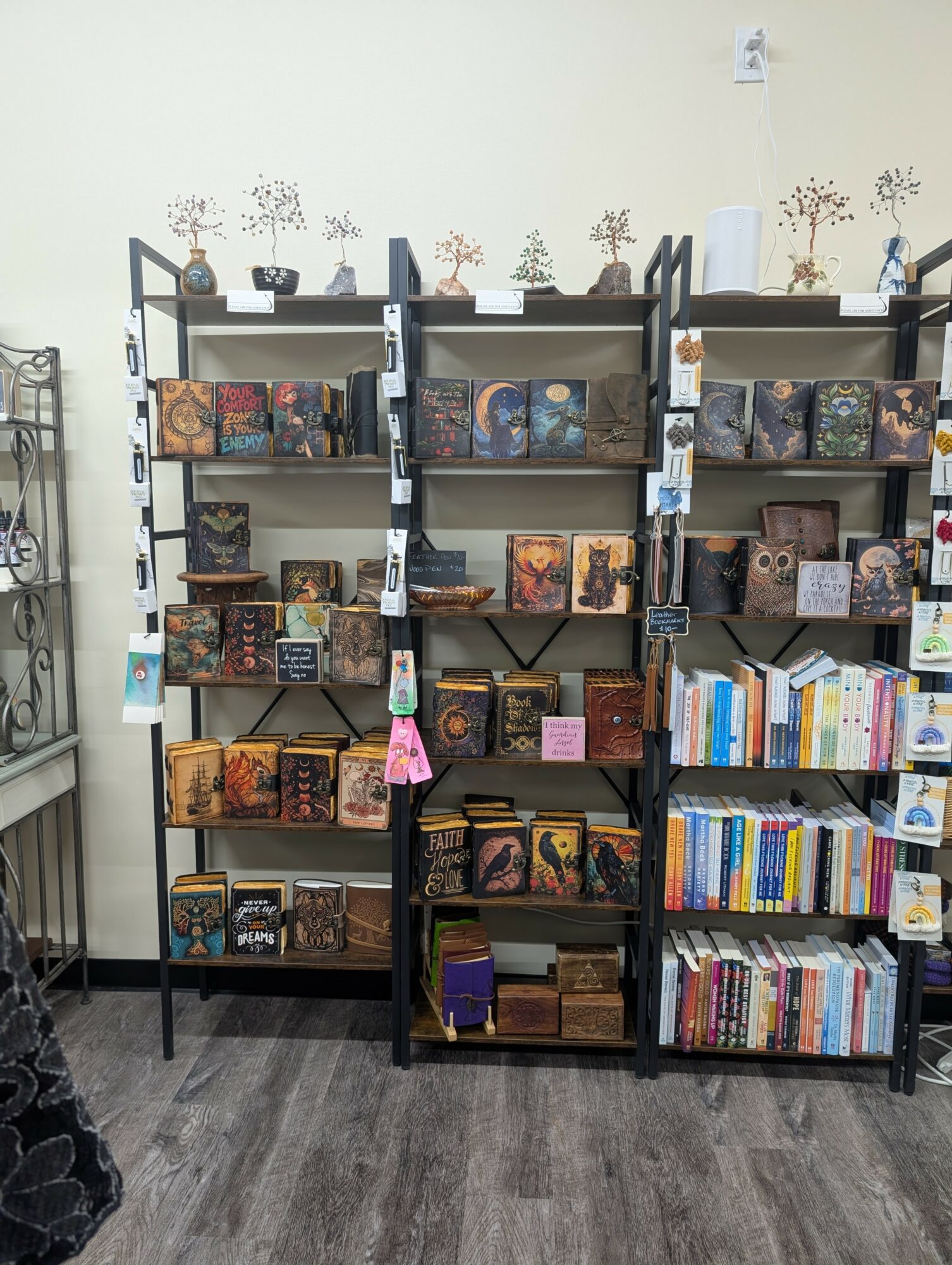 Three black bookshelves filled with books and decorative items against a white wall, on a dark floor.