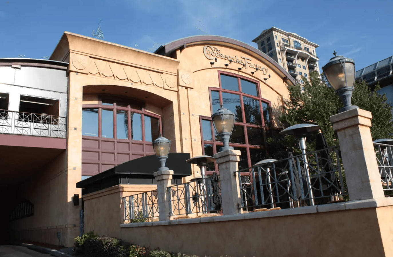 Building with large windows, decorative facade, and outdoor lamps, under a blue sky.