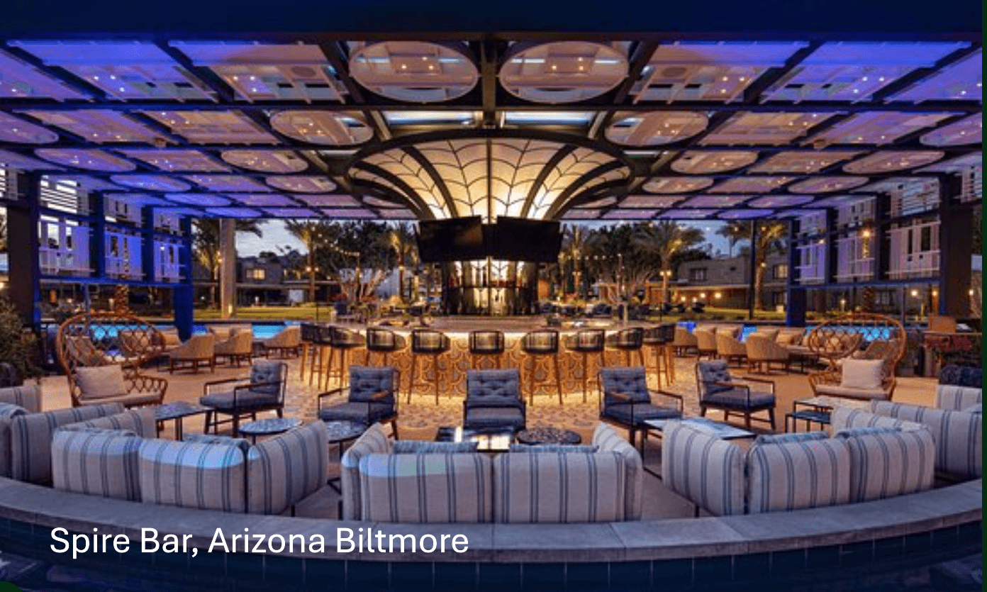 Indoor bar with seating, illuminated ceiling, and large windows showing outdoor cityscape, at Arizona Biltmore.