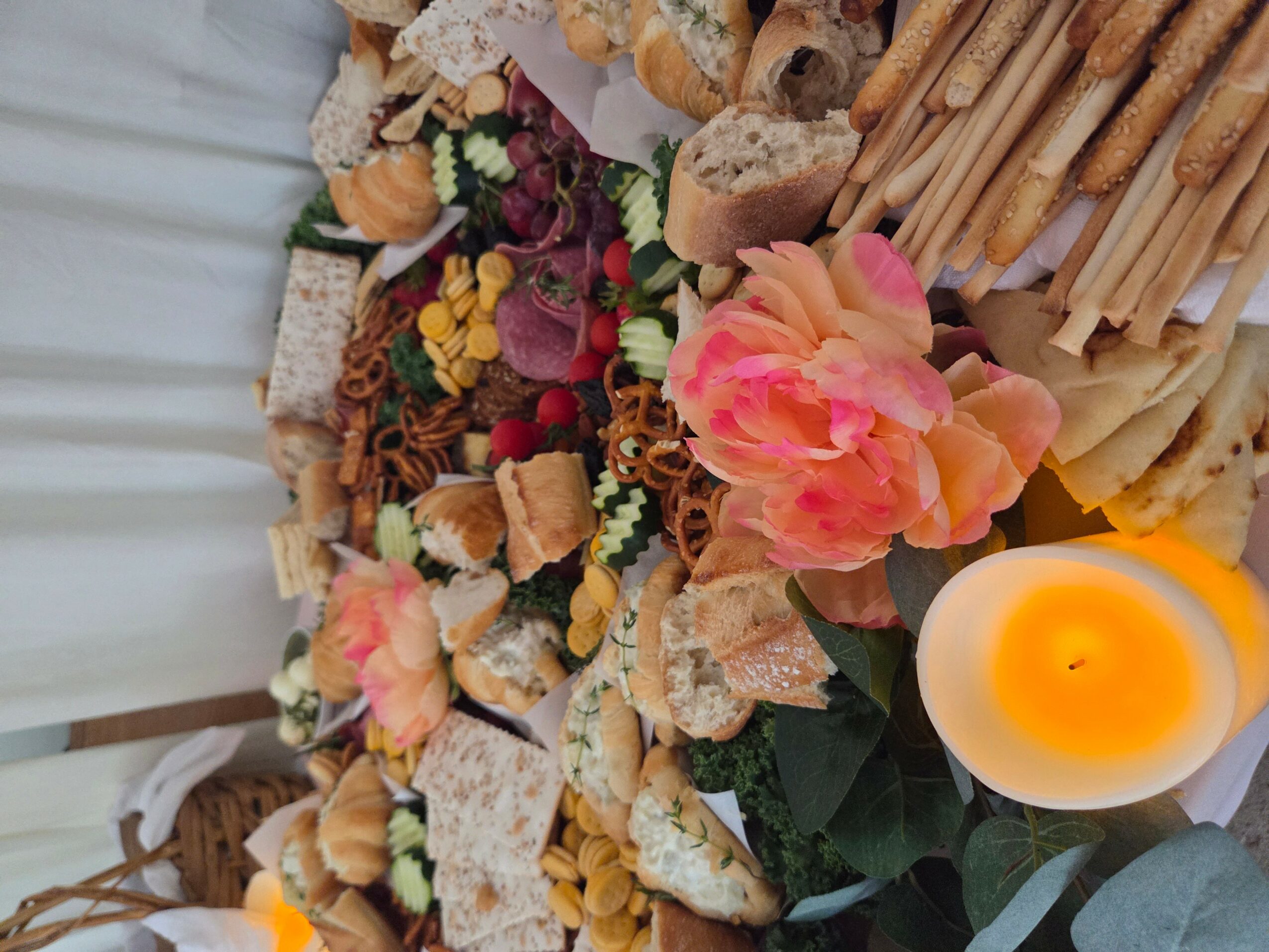 A table with various food items, flowers, and a lit candle, viewed from above.