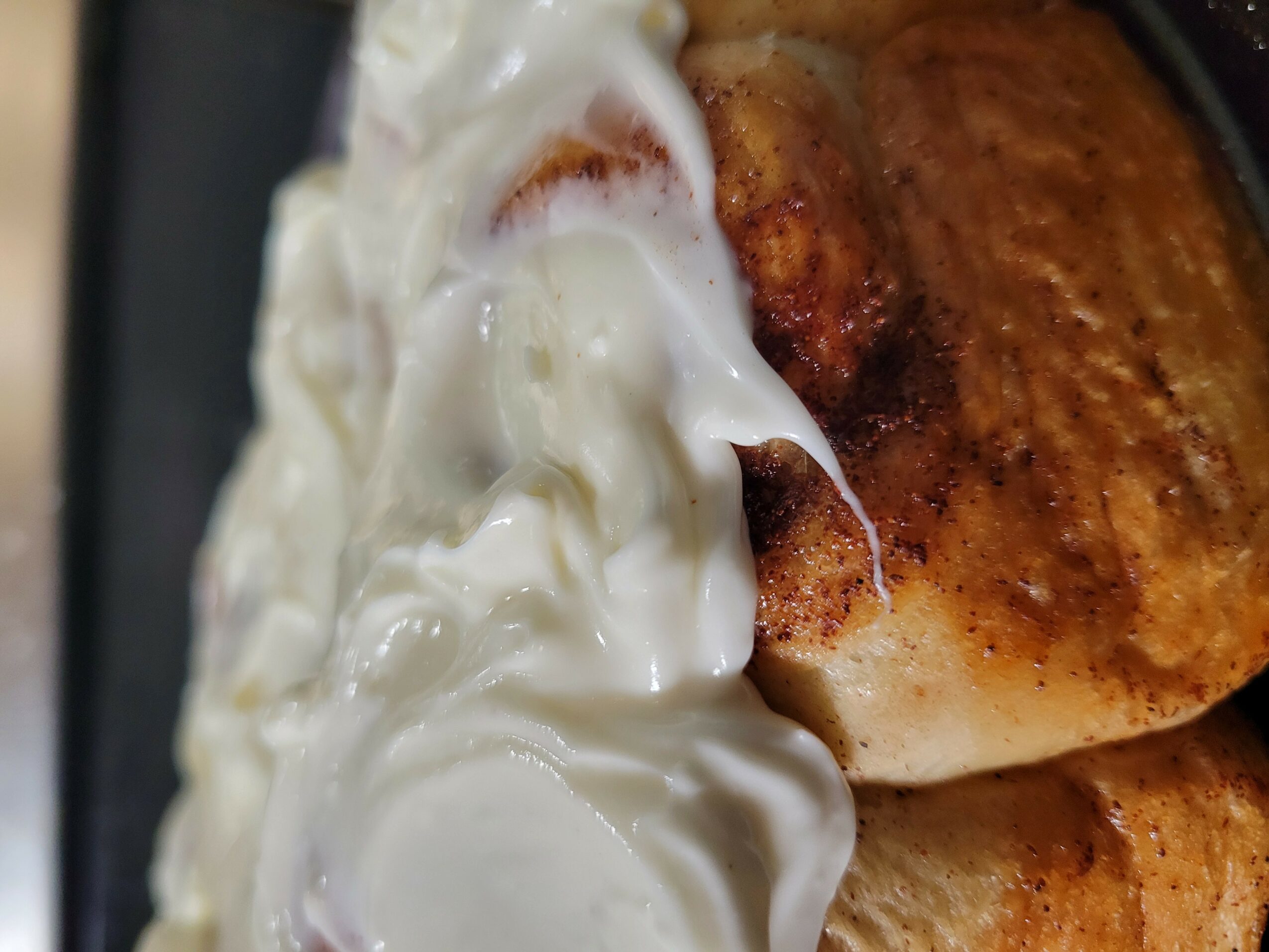 Close-up of a dessert with whipped cream and a baked item, possibly bread or pastry, with cinnamon or spice on top.