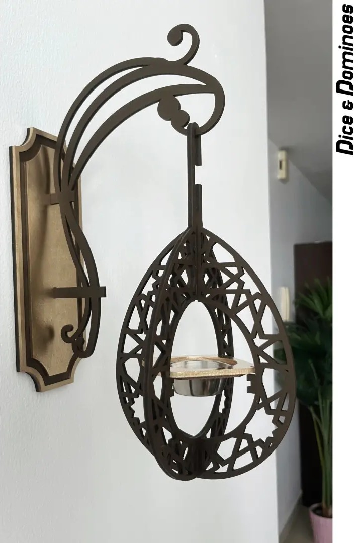 Decorative hanging lantern with intricate openwork design, mounted on a wall, with a small shelf inside, in a room setting.