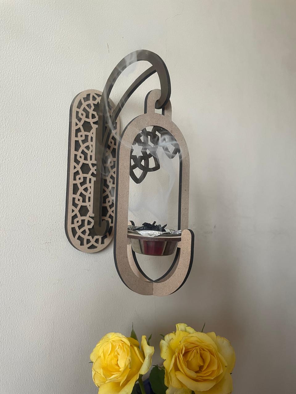 Decorative wall mirror with a candle holder and yellow roses below, mounted on a plain wall.