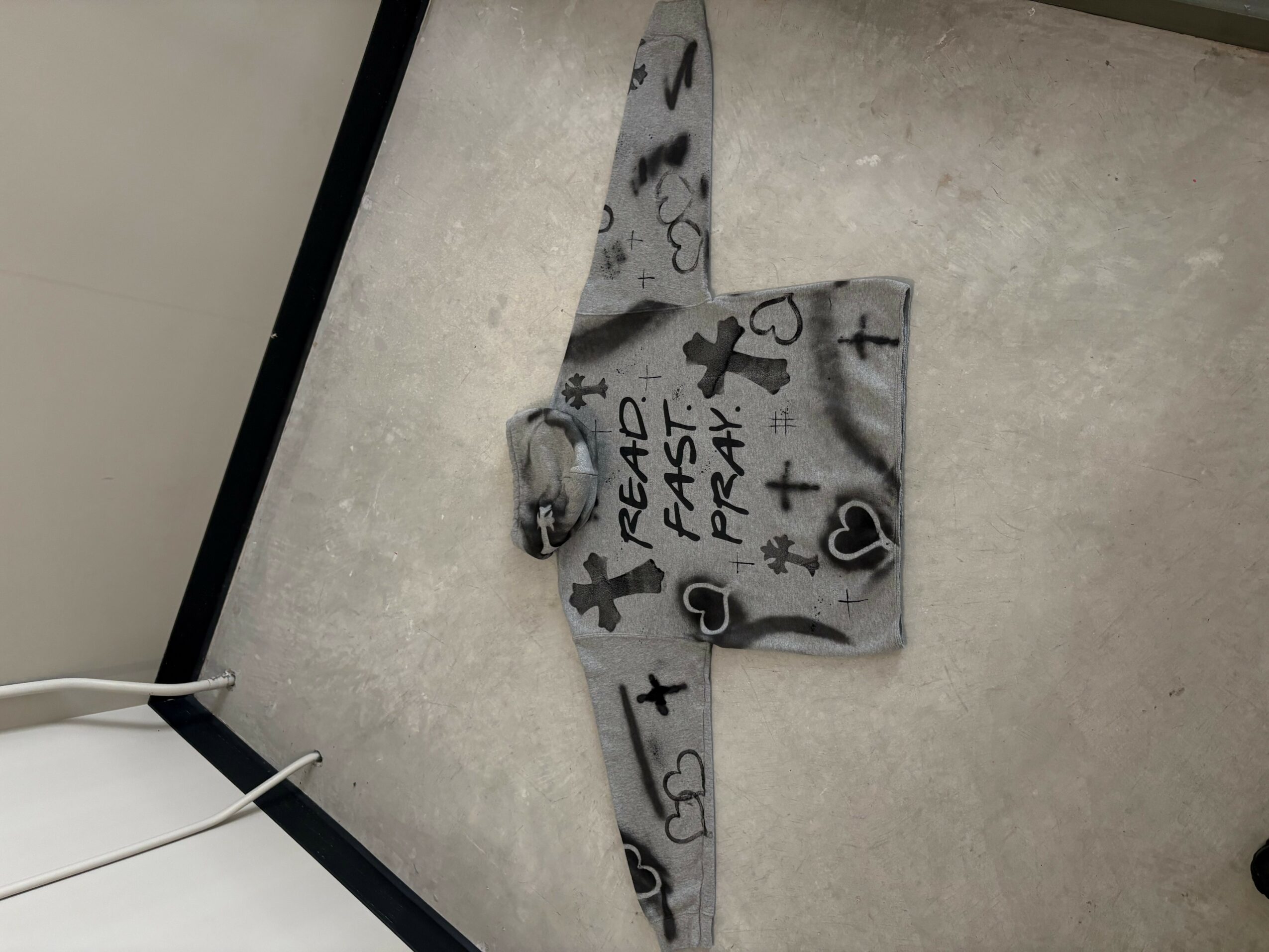 A gray object with black and white symbols and text, lying on a gray surface, viewed from the side.