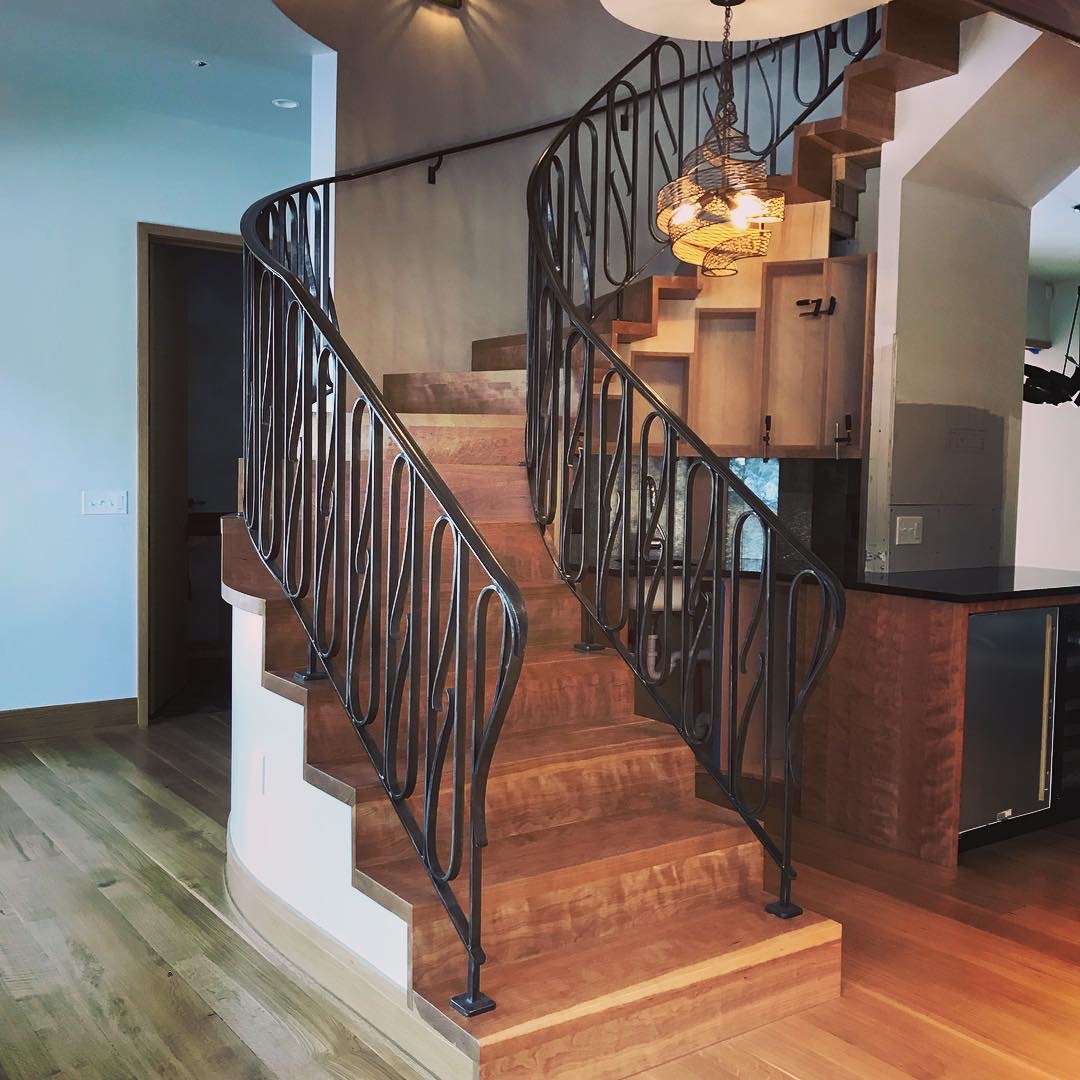 Curved staircase with black metal railing and wooden steps in a modern interior.