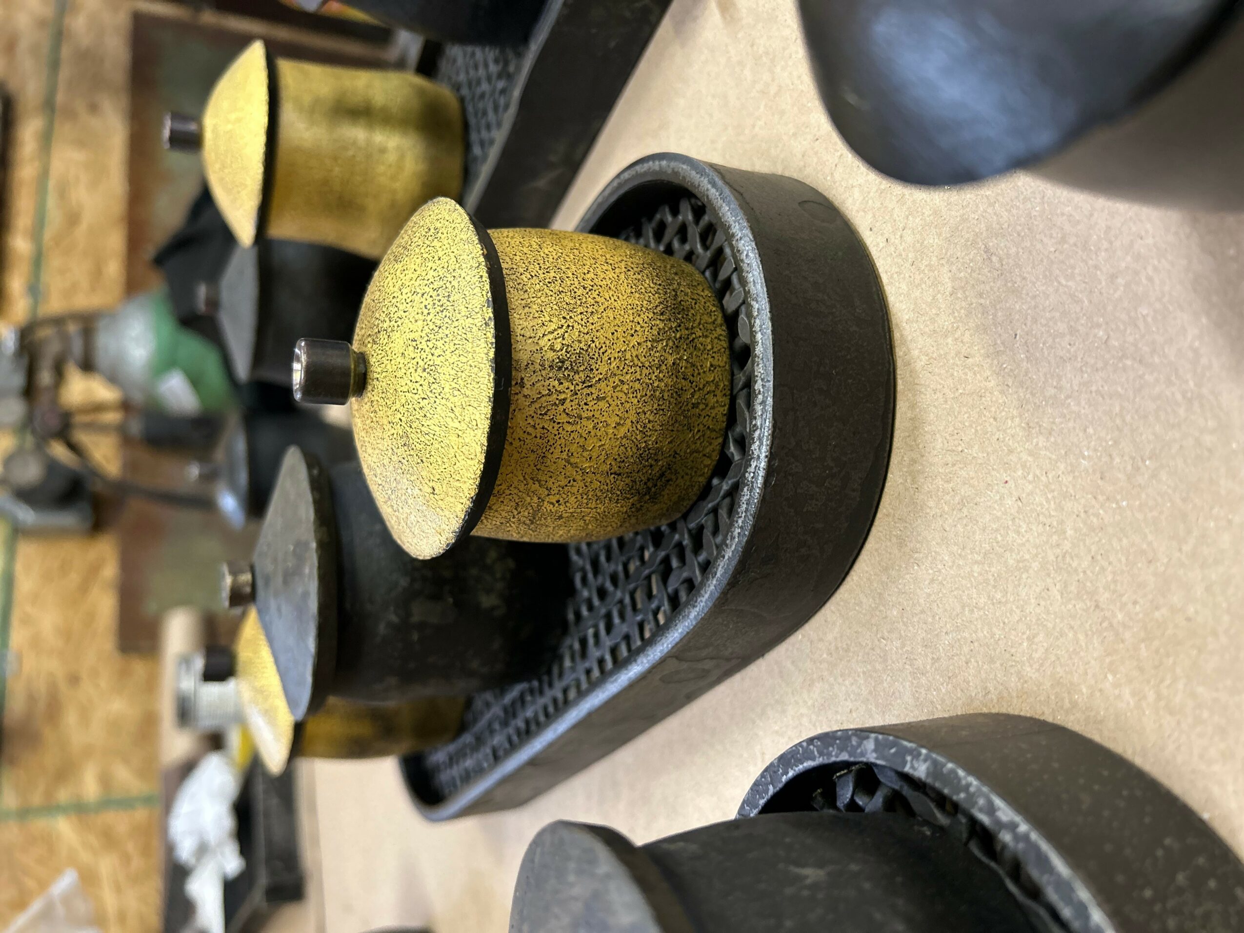 Close-up of a yellow coffee capsule on a black tray, with other capsules in the background.
