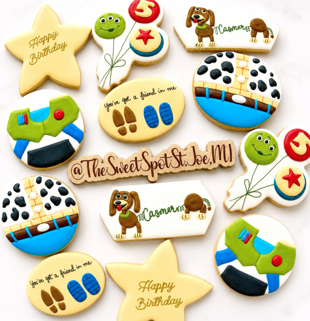 Assorted decorated cookies with birthday and animal themes, including stars, balloons, dogs, and a message, on a white background.