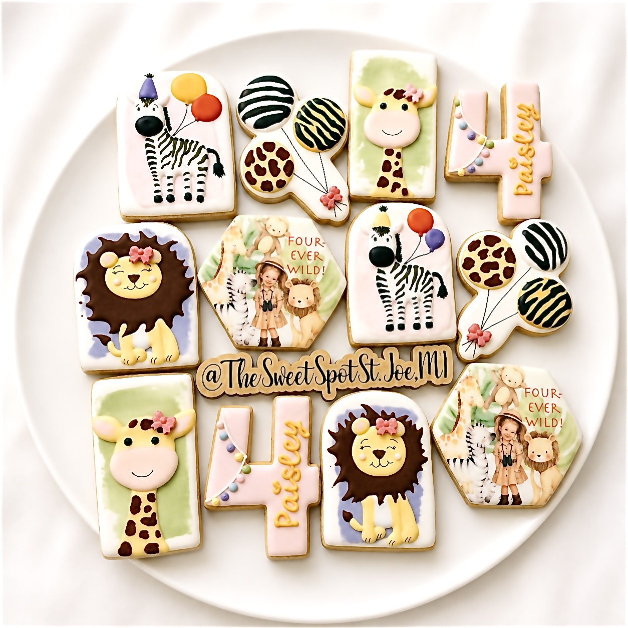 Decorative cookies with animal and jungle themes, including lions, zebras, giraffes, and colorful patterns, arranged on a white plate.