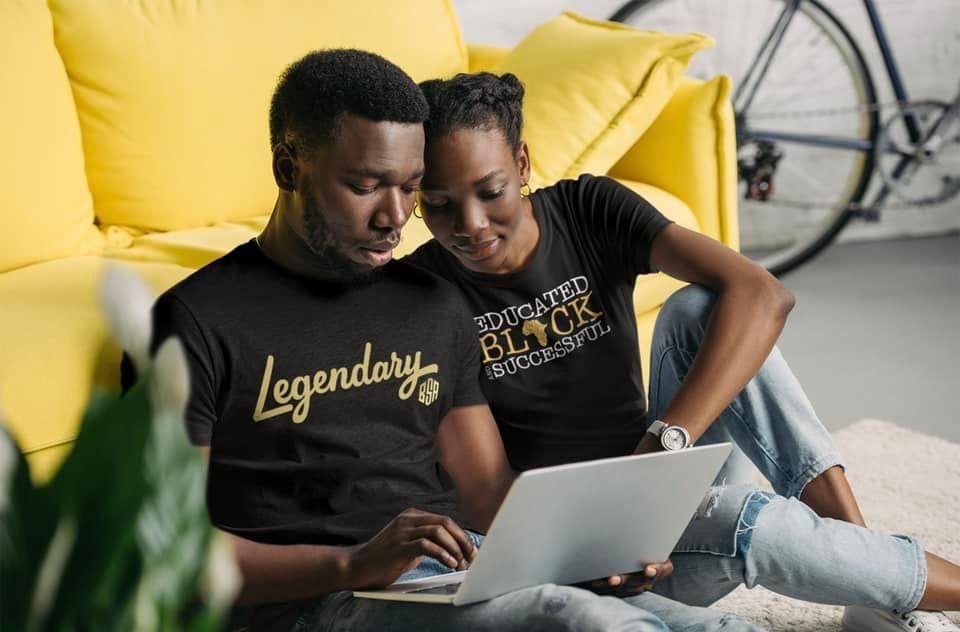 Two people sitting on a yellow couch looking at a laptop together, with a bicycle in the background.