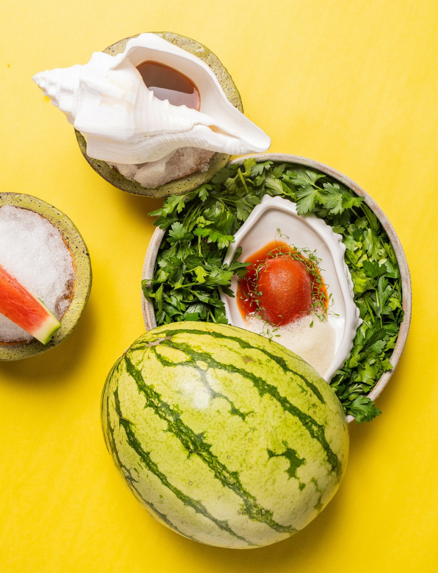Watermelon, yogurt with tomato, and a drink on a yellow background.