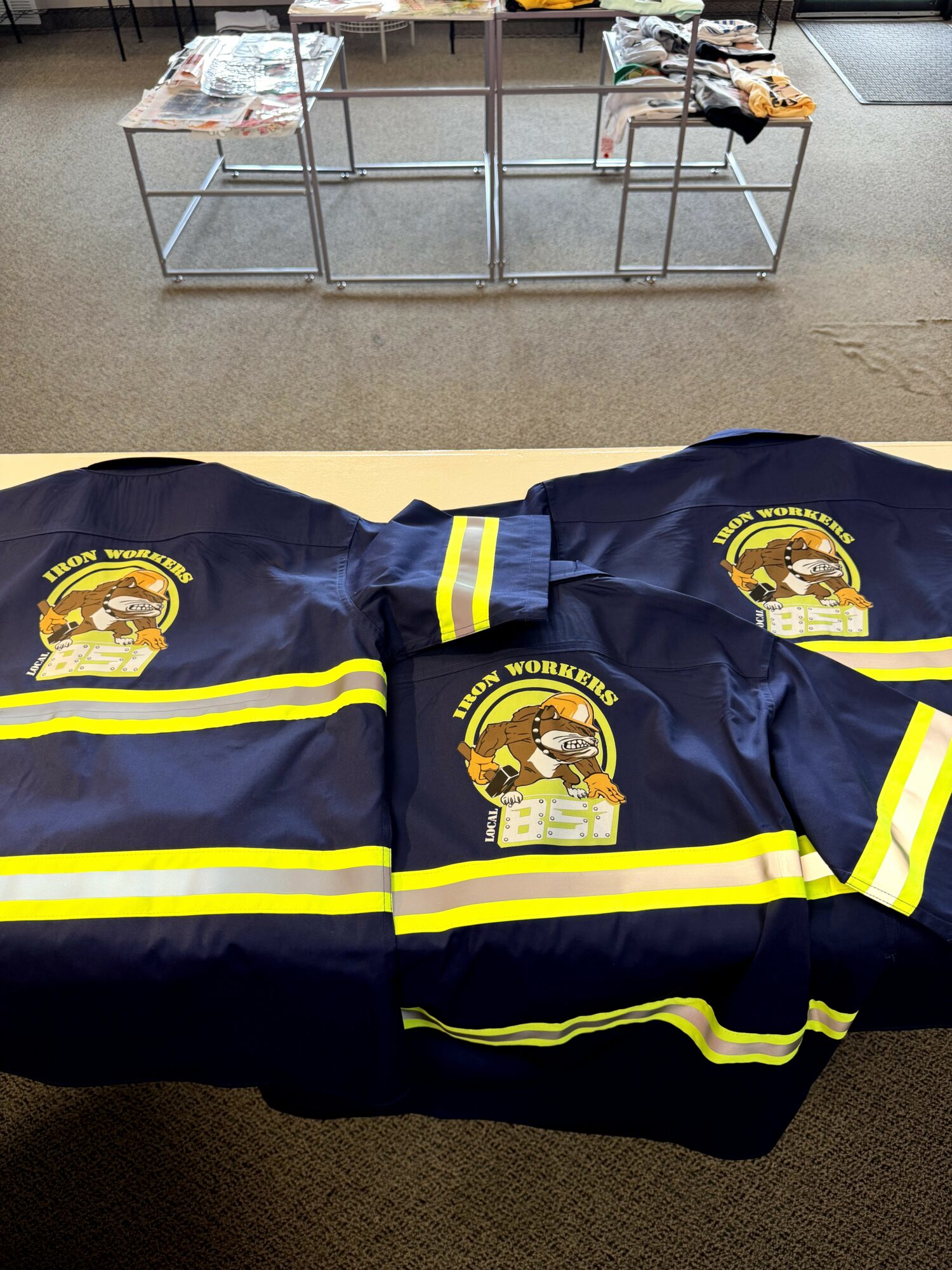 Two navy blue firefighter jackets with yellow reflective stripes and patches, laid out on a table.