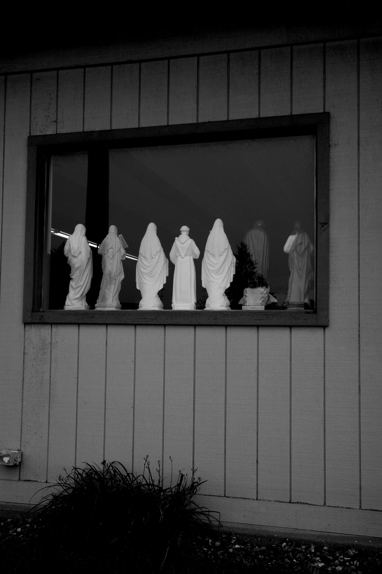 View of Jesus on the cross through a window, with a dark sky in the background.