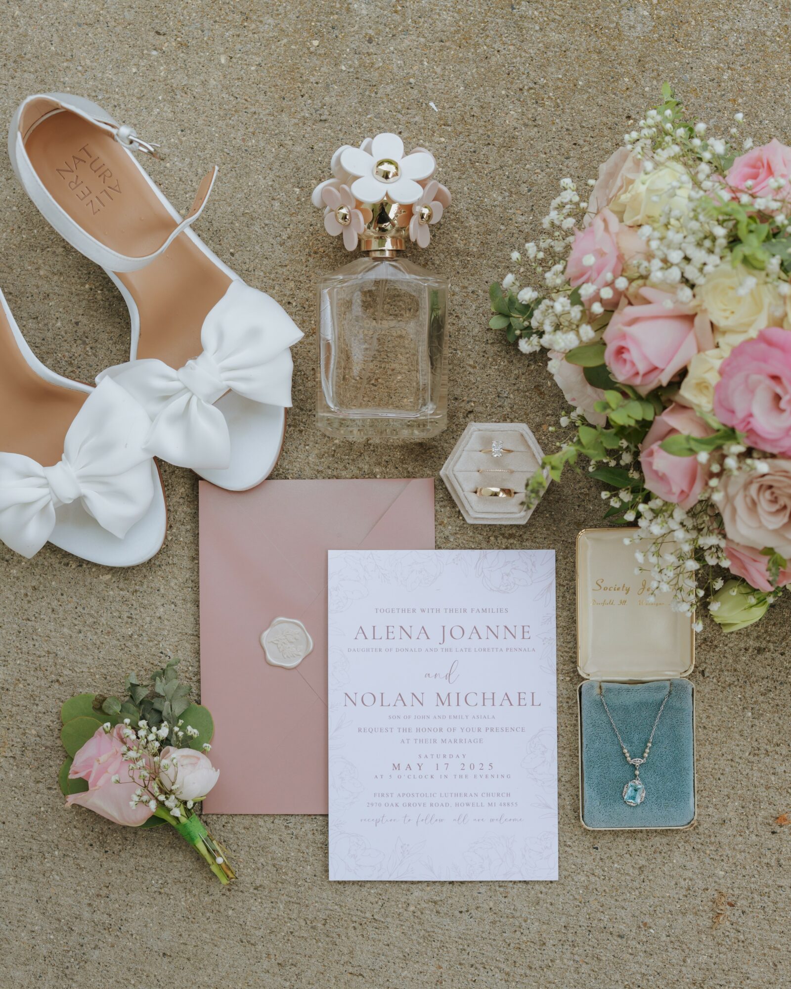 Wedding invitation, shoes, flowers, perfume, jewelry, and a pink envelope arranged on a surface.