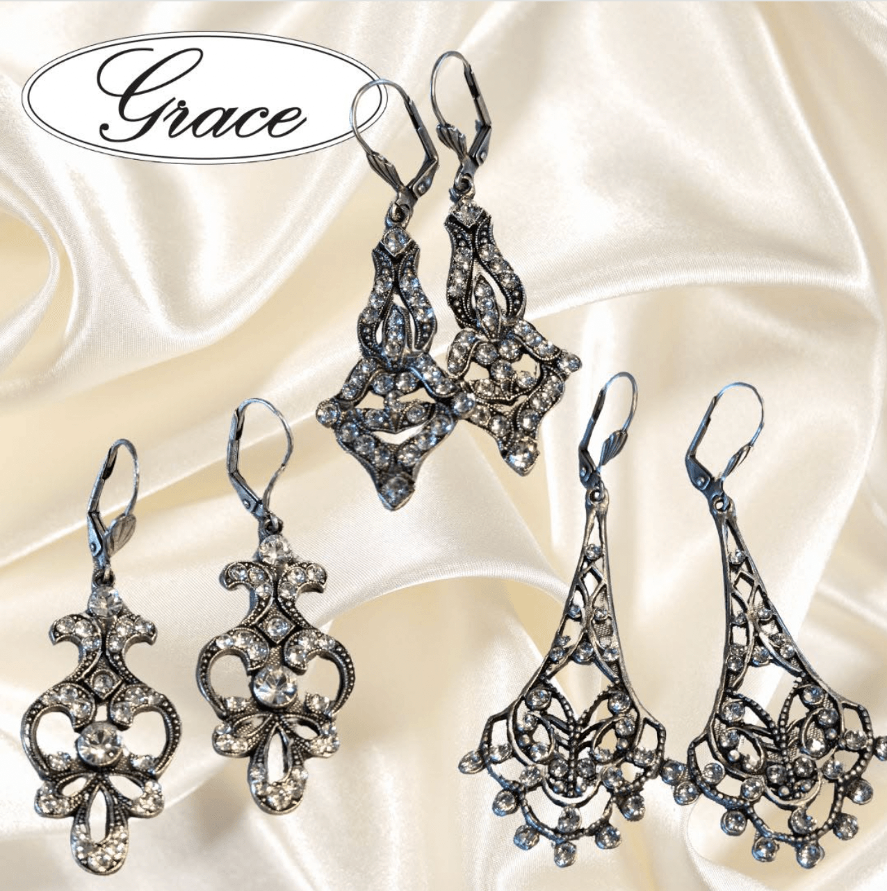 Set of five ornate earrings with intricate metalwork and gemstones displayed on satin fabric.