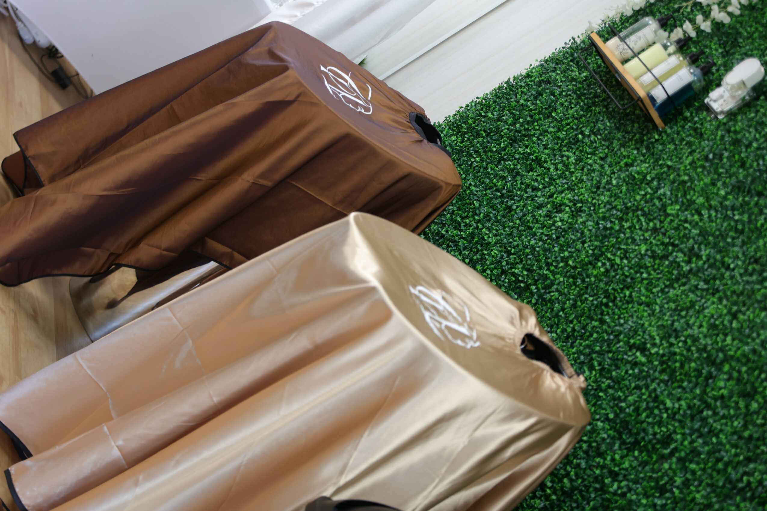 Two covered objects, one brown and one beige, in a room with green wall and wooden floor.