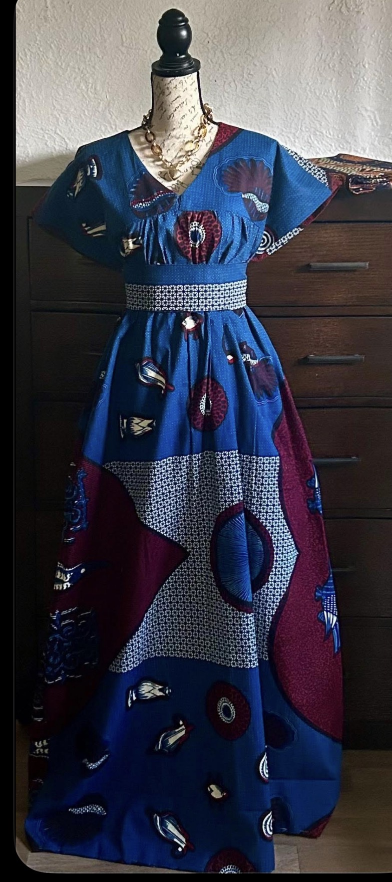 Long dress with blue, red, and white geometric and abstract patterns displayed on a mannequin.