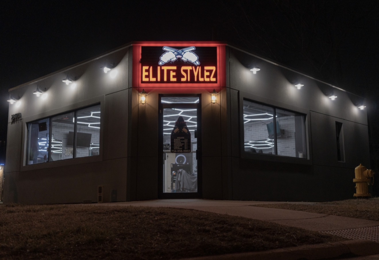 Night view of a building with illuminated windows and a sign that reads 'ELITE STYLEZ' above the entrance.