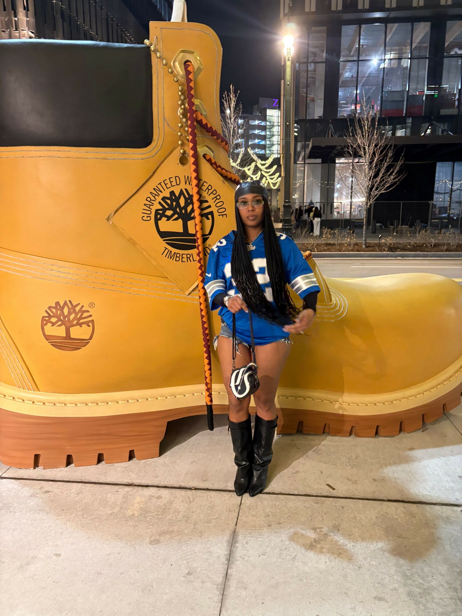 Person standing next to a large yellow structure with a logo, in an outdoor urban setting at night.