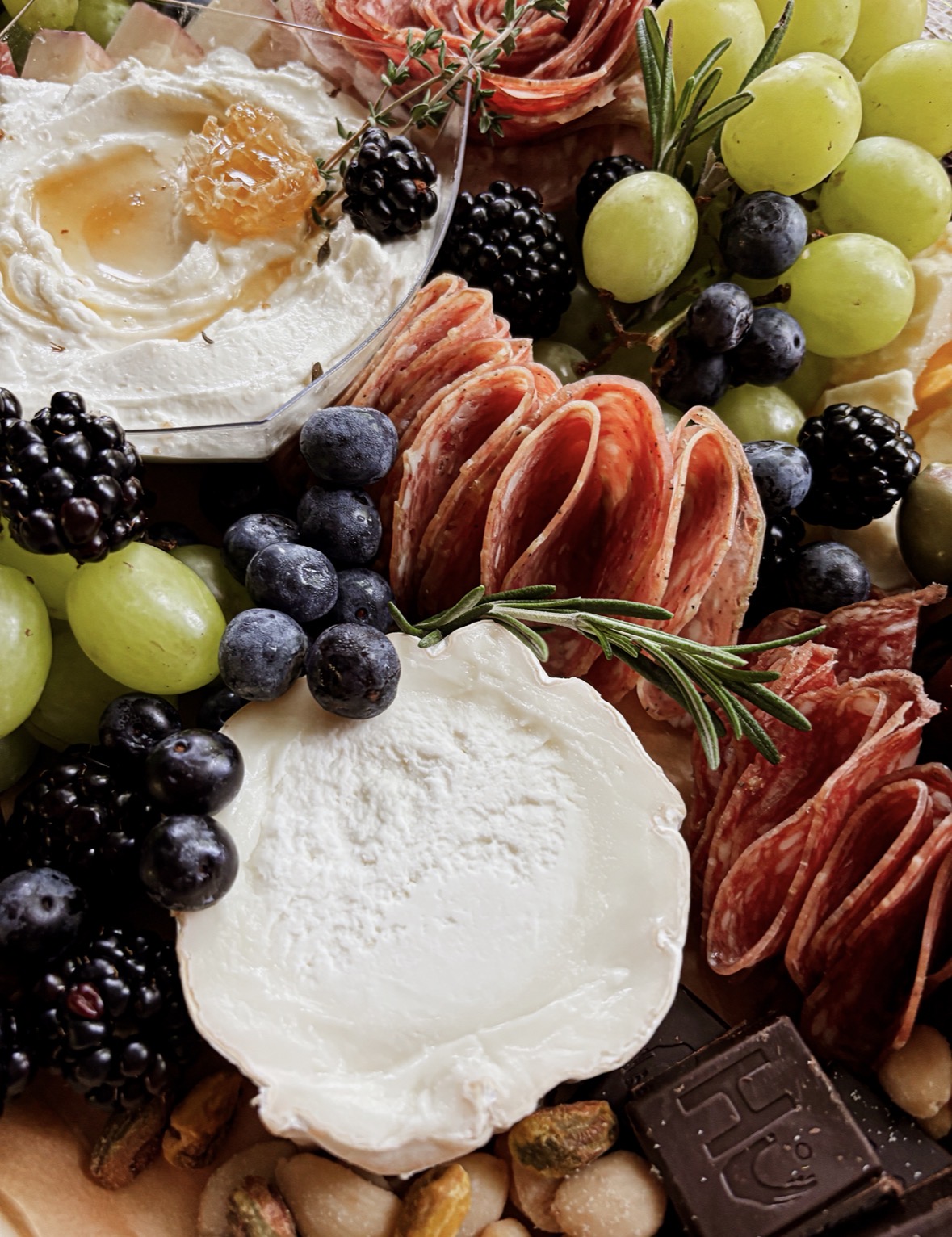 Assorted fruits, cheese, and a soft cheese wheel arranged on a platter.