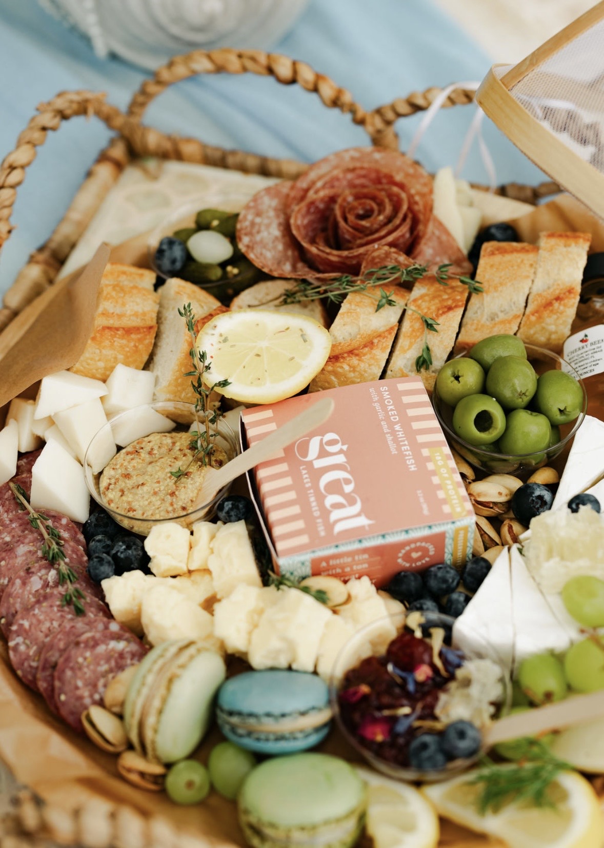 Assorted cheeses, bread, grapes, olives, and a rose-shaped item on a platter with a pink box labeled 'gift'.