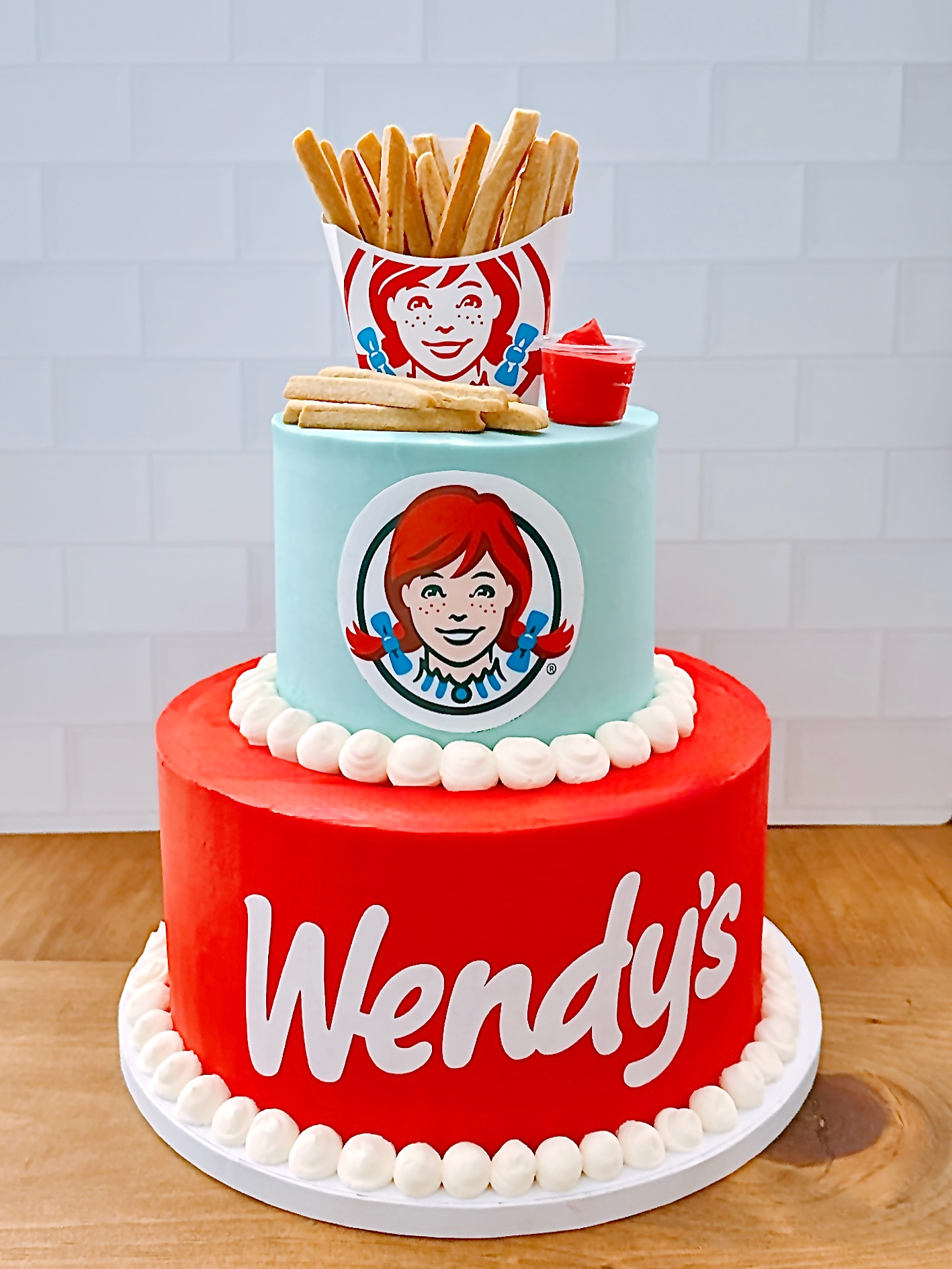 Cake decorated as Wendy's fast-food items with fries, burger, and drink, featuring Wendy's logo, on a white background.