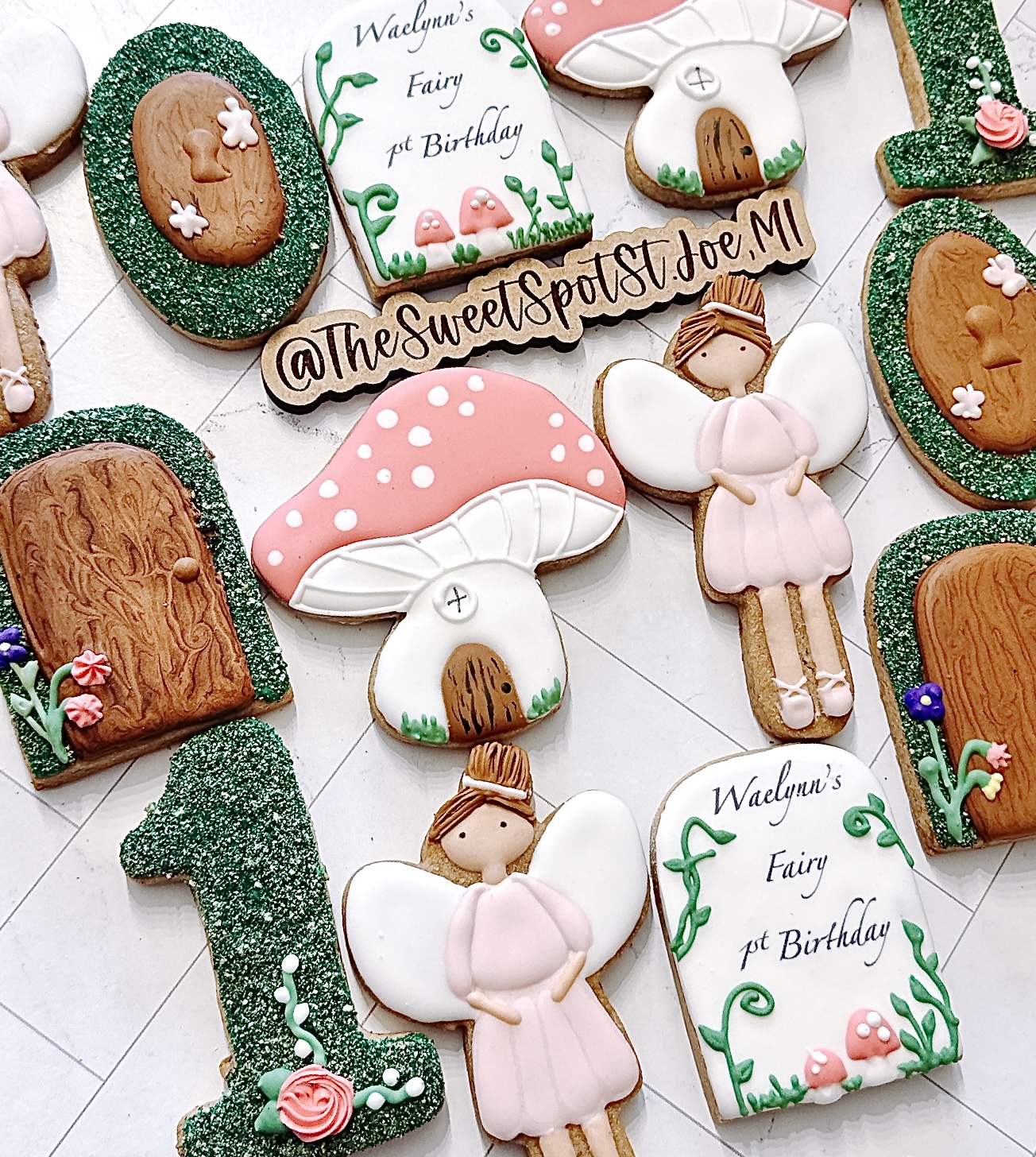 Decorative cookies with fairy tale theme, including a girl, mushroom, and birthday message, arranged on a white surface.