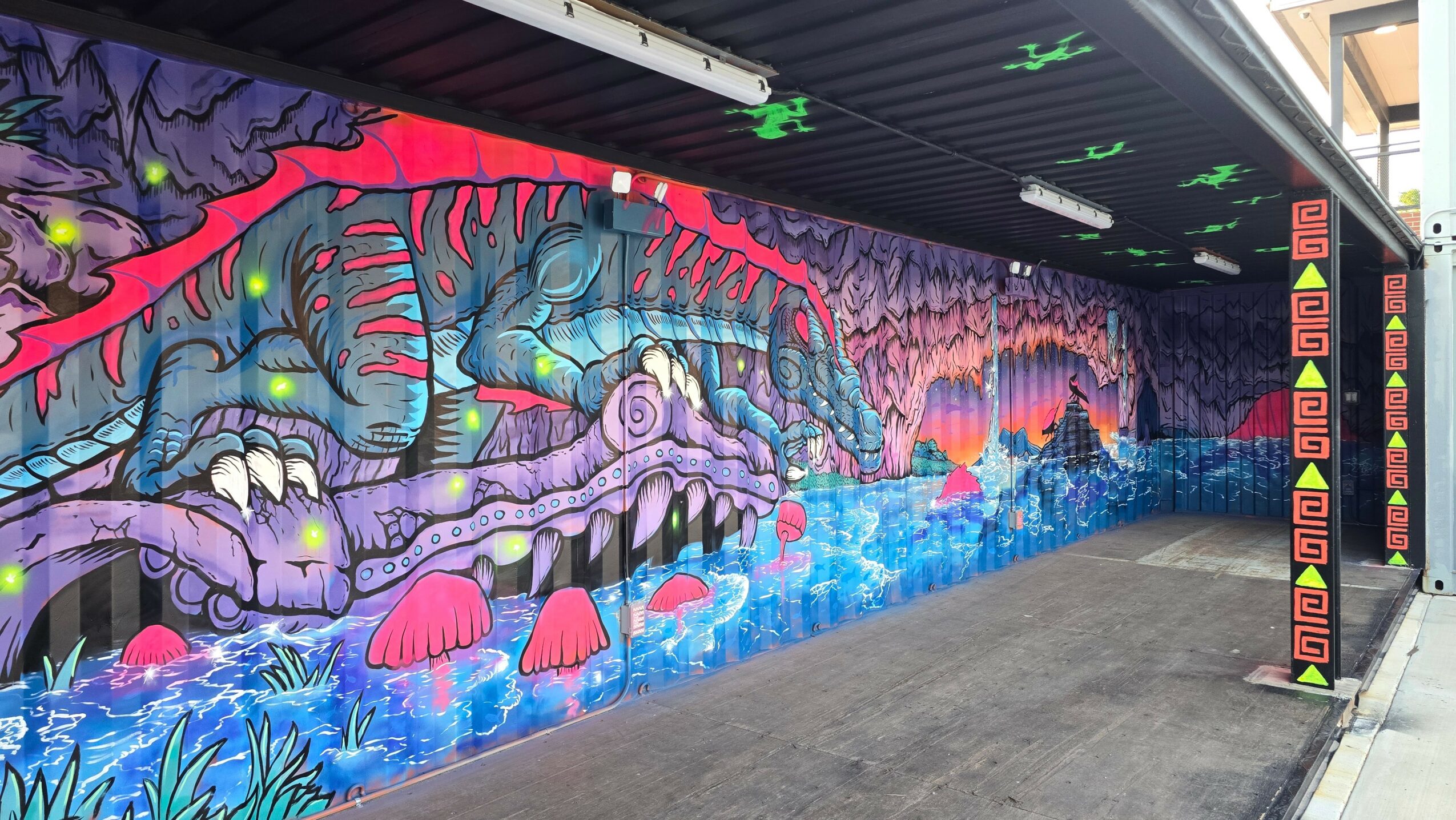 Colorful mural of fantastical creatures and landscape with mushrooms and glowing elements on a wall.