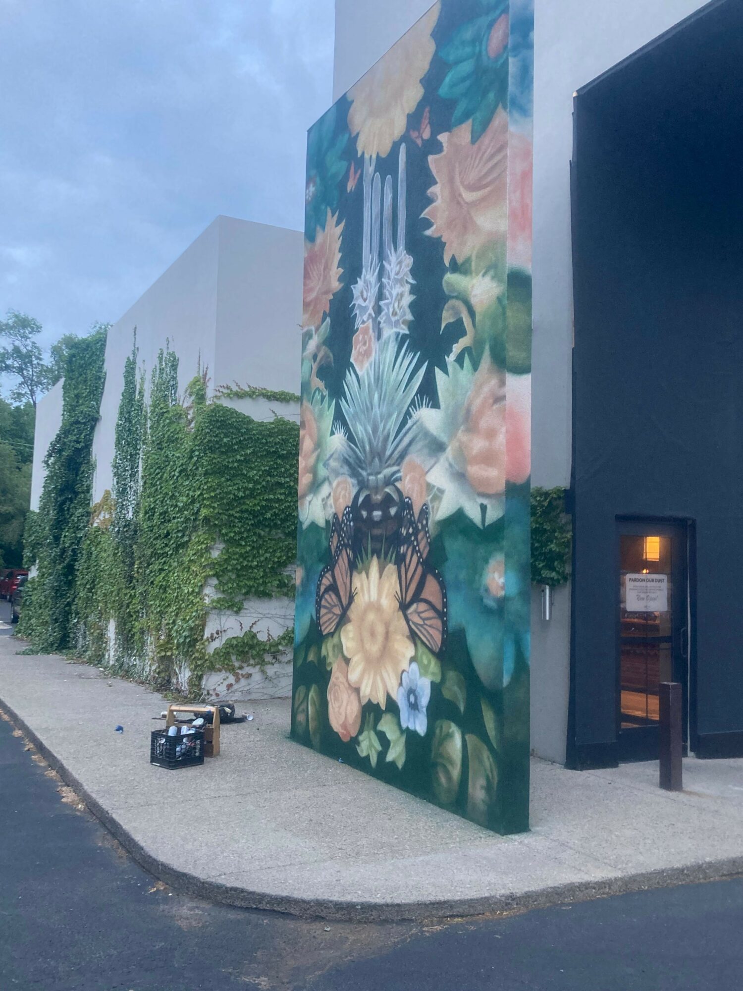 Colorful floral mural on a wall with trees and a sidewalk in front.