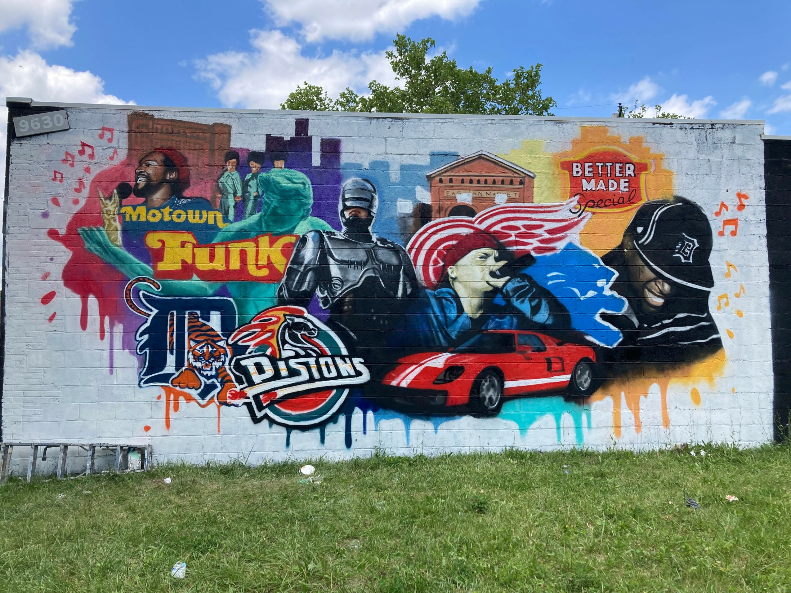 Colorful mural featuring musicians, a police officer, a red sports car, and various cityscape elements, with musical notes and graffiti style art.