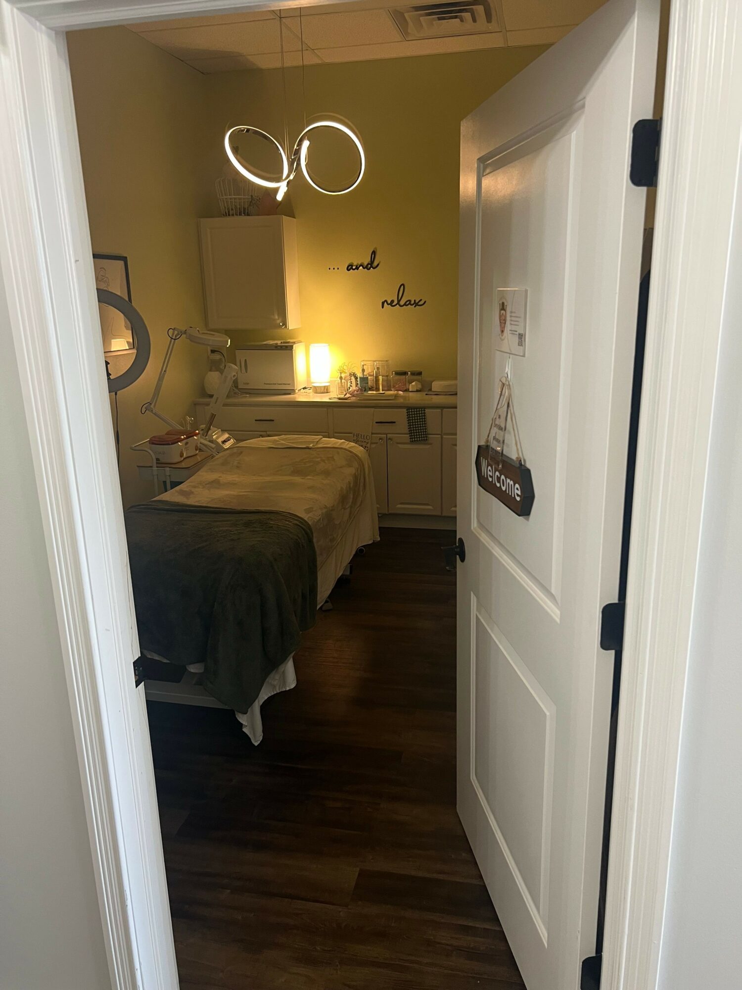 Bedroom with bed, nightstand, lamp, and wall decor, viewed from doorway, with hardwood floor and yellow walls.