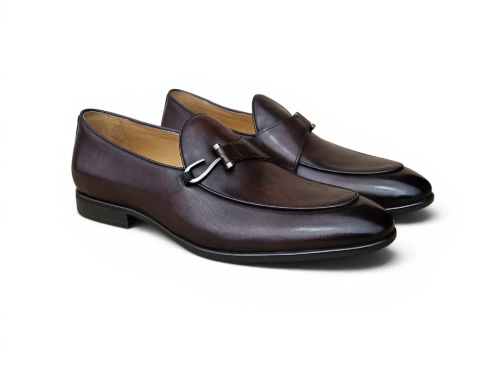 Pair of brown leather loafers with a metal buckle detail, placed on a white background.