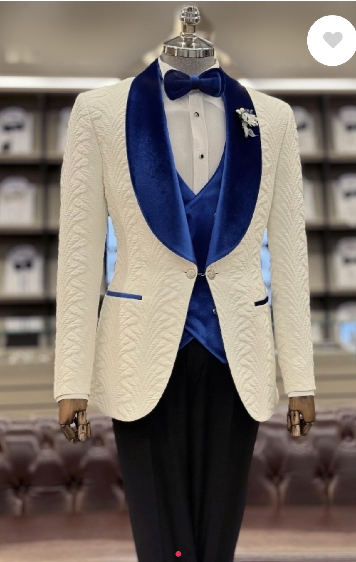 Mannequin dressed in a white textured blazer with blue satin lapel, black bow tie, and black pants, in a store setting.