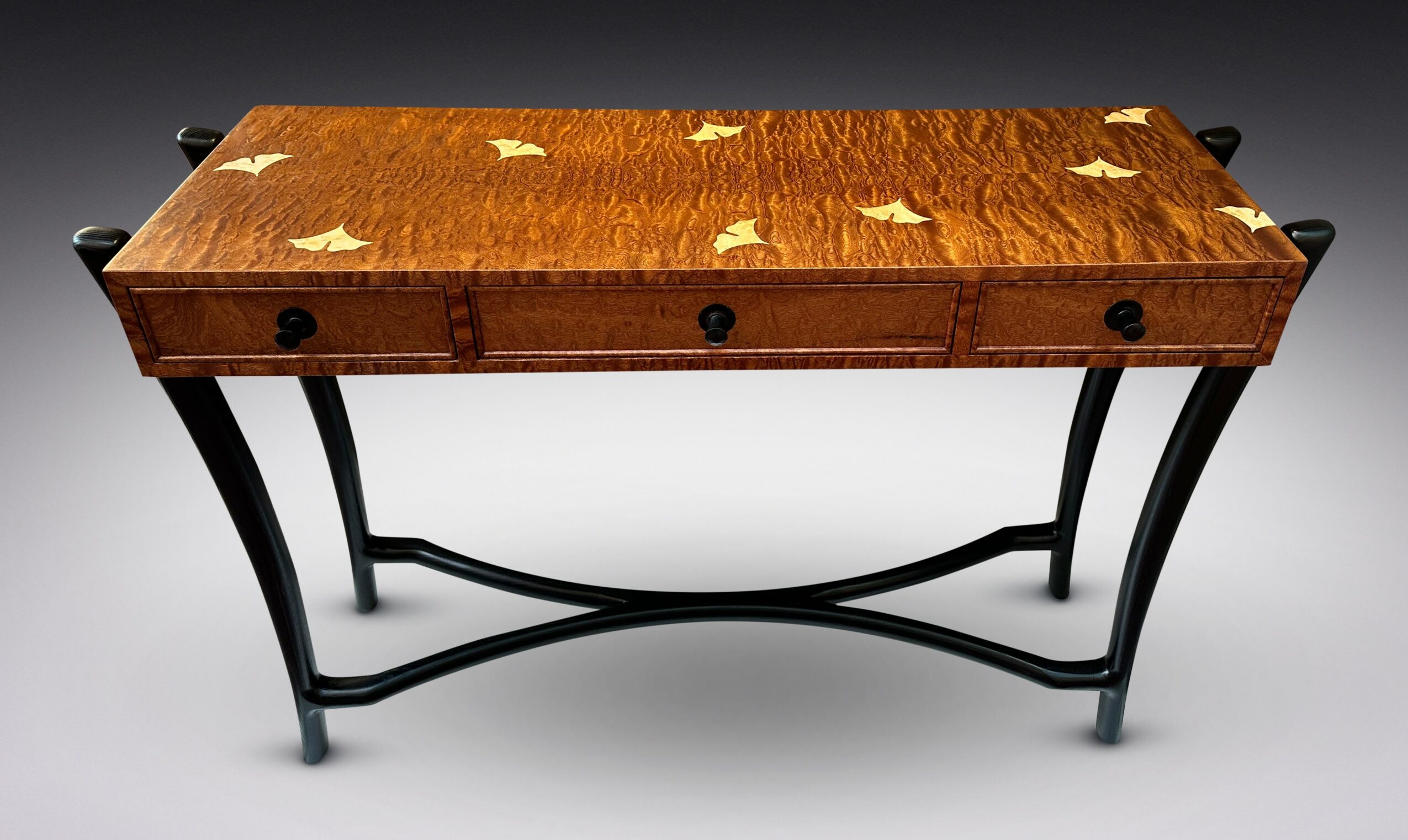 Wooden table with a decorative inlay top and curved black metal legs, against a plain background.
