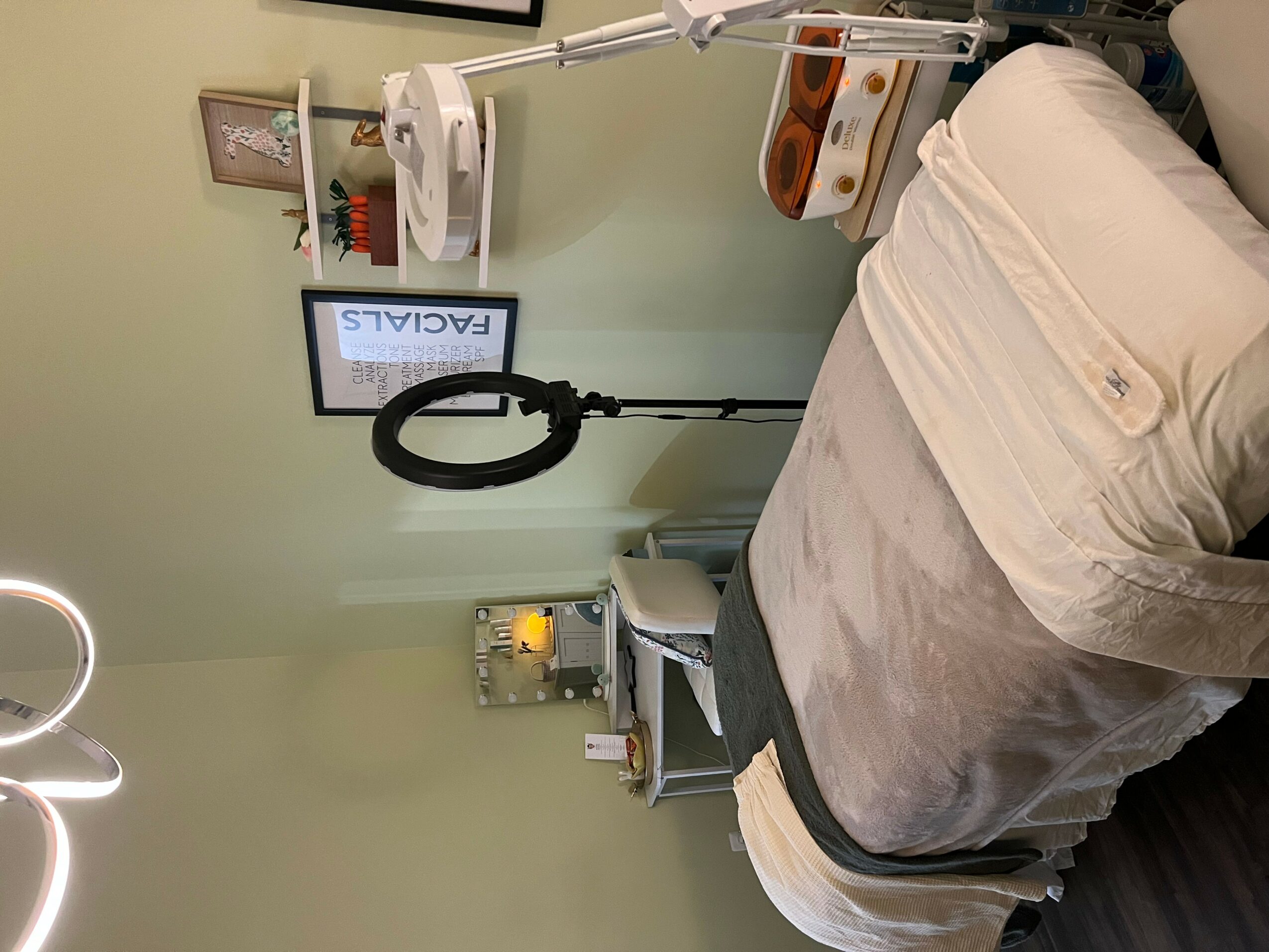 Hospital bed with beige bedding and medical equipment nearby, including a monitor and a lamp, in a clinical room.