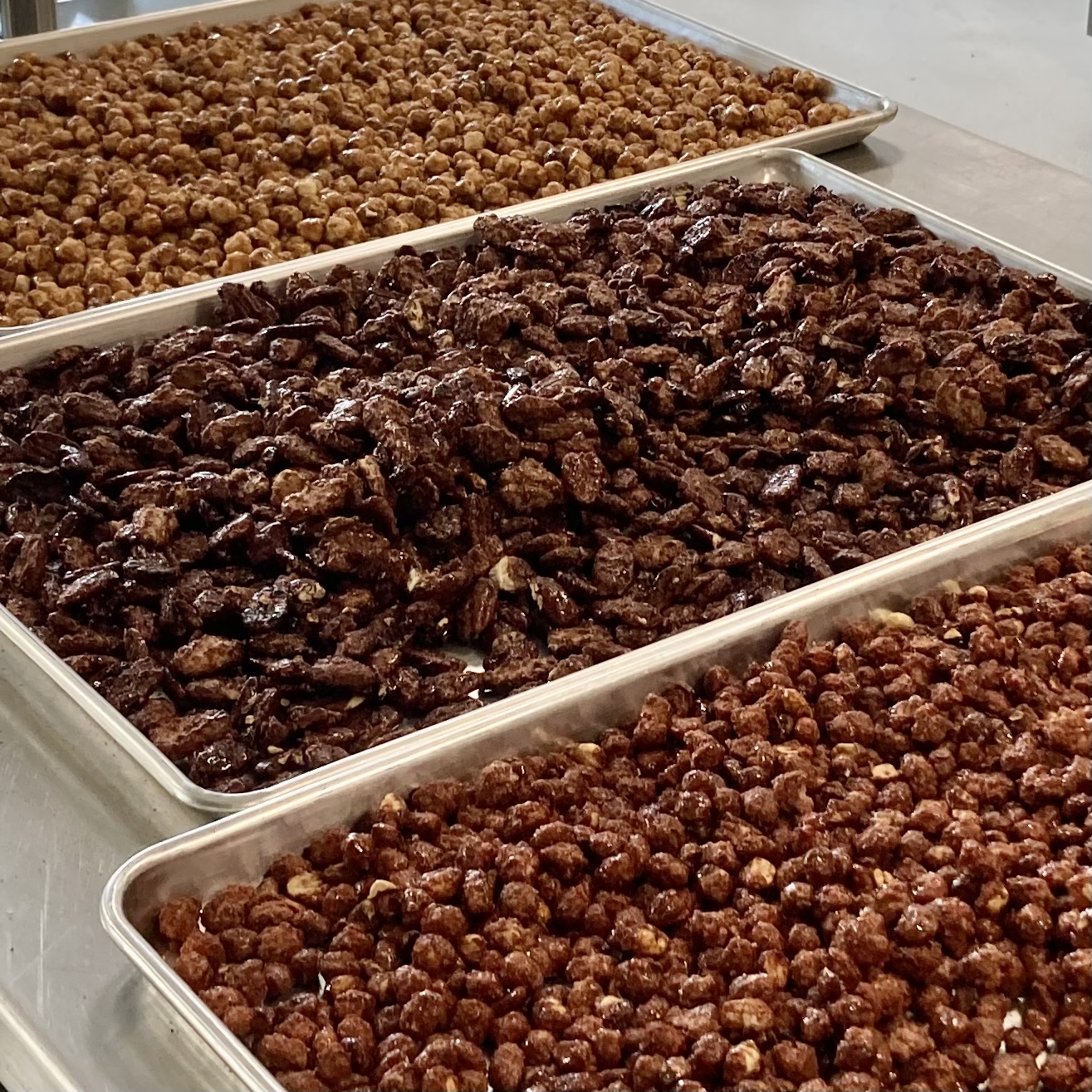 Three trays of cooked ground meat and beans on a countertop, with the middle tray containing dark cooked meat, and the top and bottom trays containing beans.