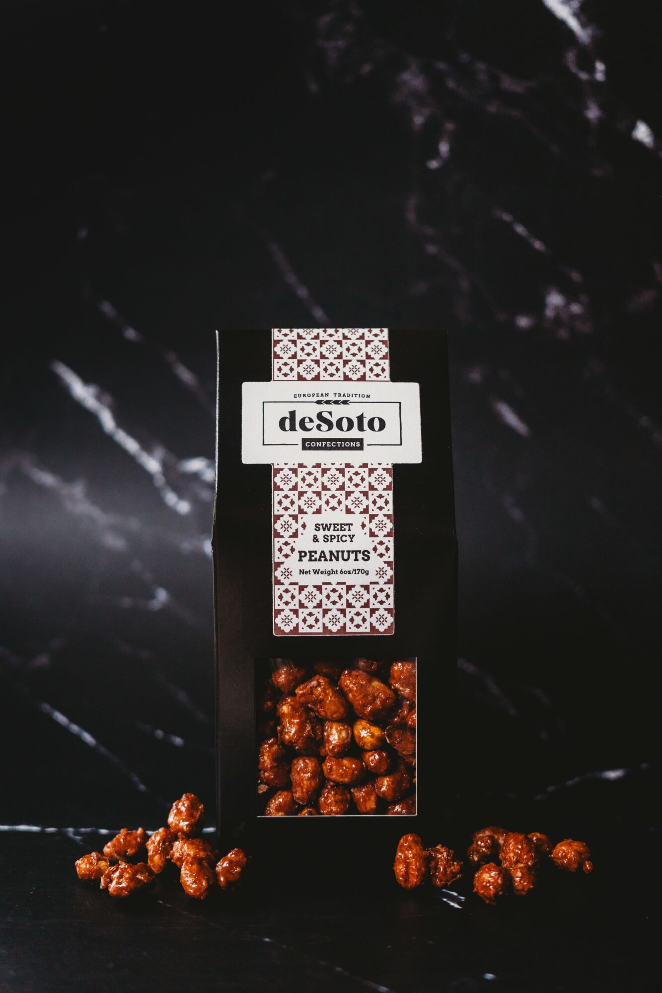 Box of deSoto caramel popcorn with some pieces scattered around, set against a dark background.