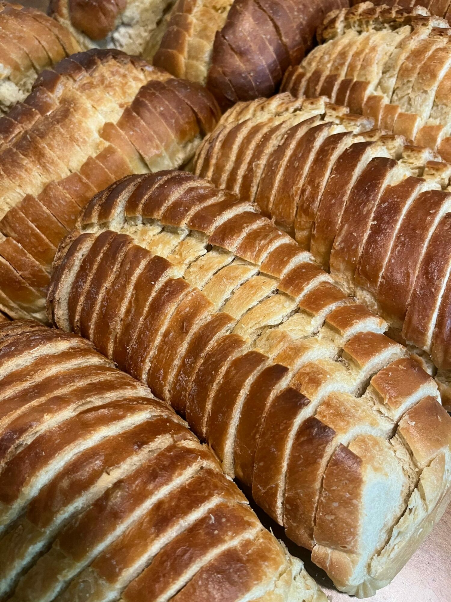 Sliced bread loaves stacked in a display, showing golden crust and soft interior.