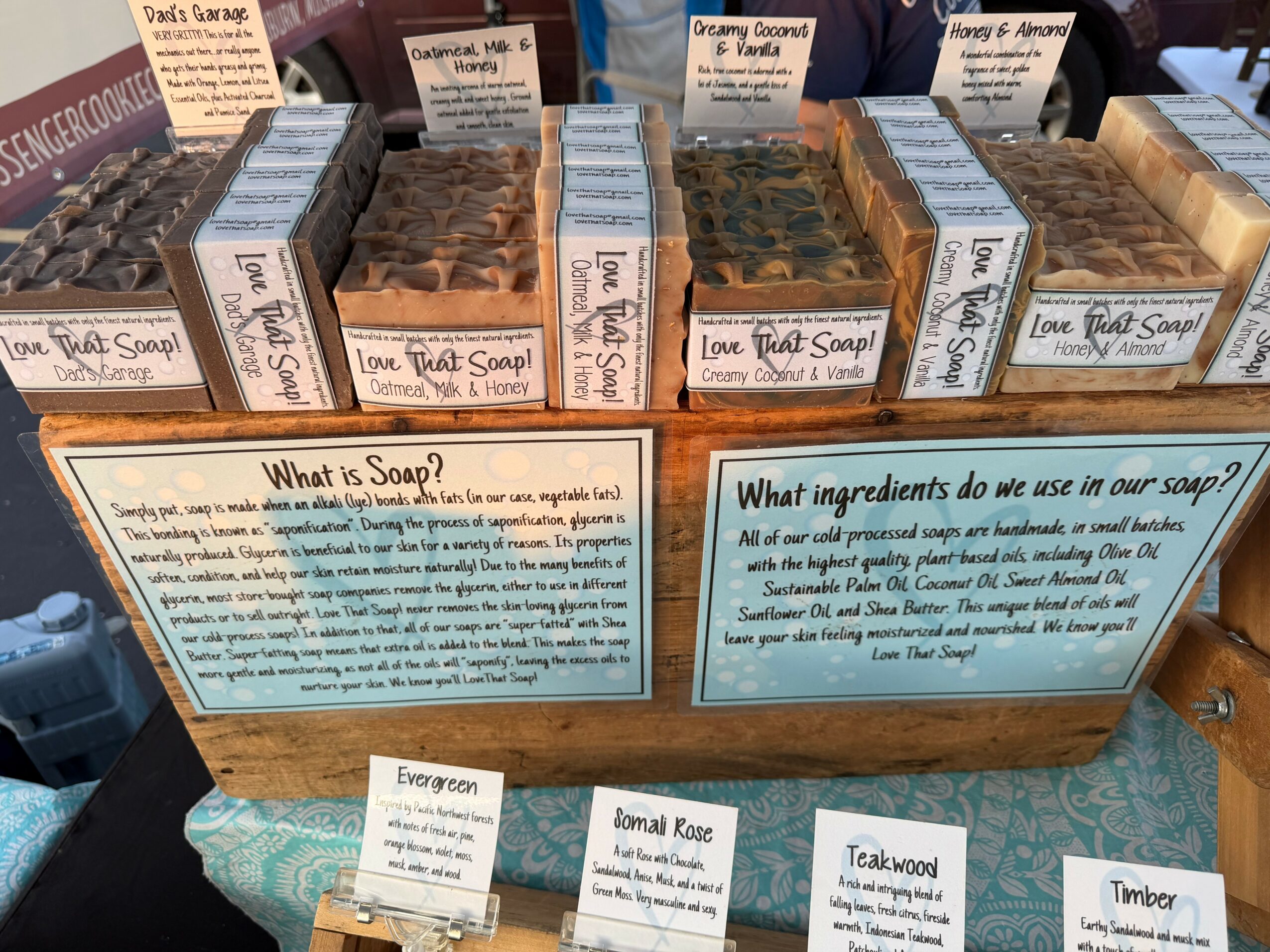 Display of soap bars with informational signs about soap ingredients and usage, arranged in rows on a table.