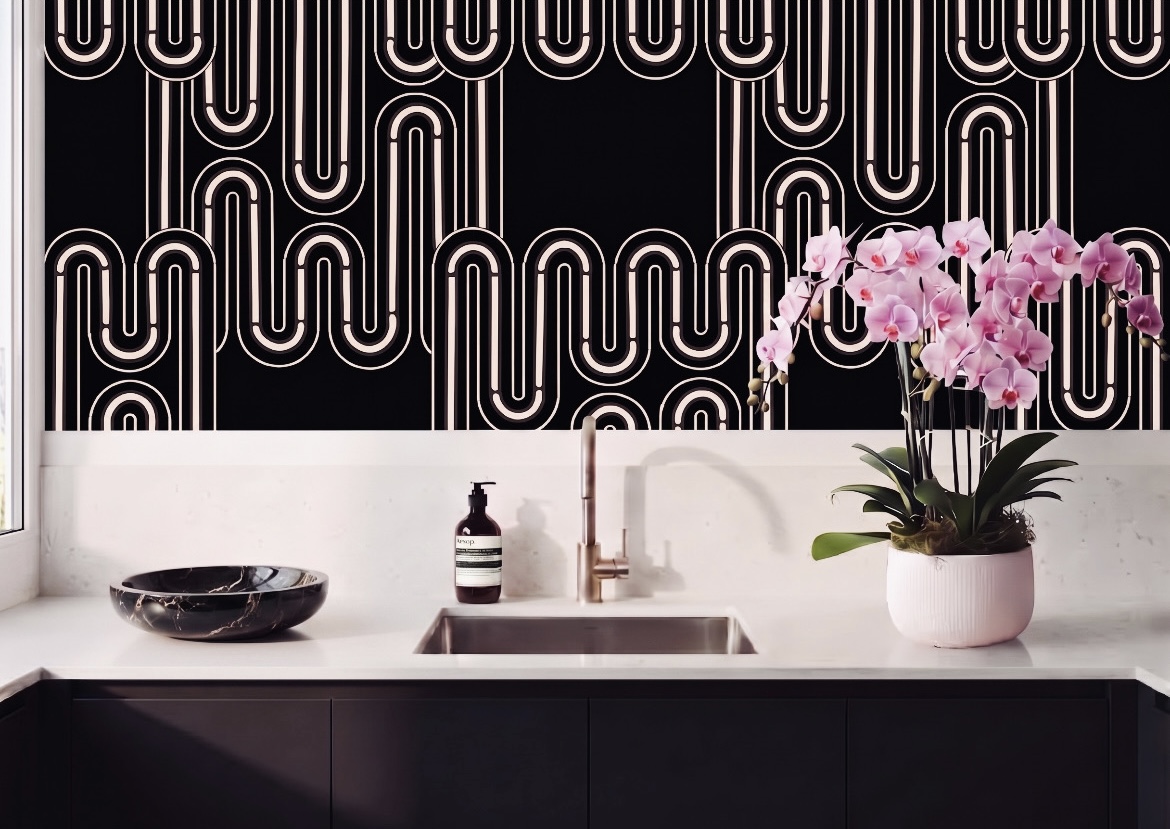 Kitchen sink with pink orchid in a white pot, black bowl, and soap dispenser on a white countertop, black and white patterned wall.