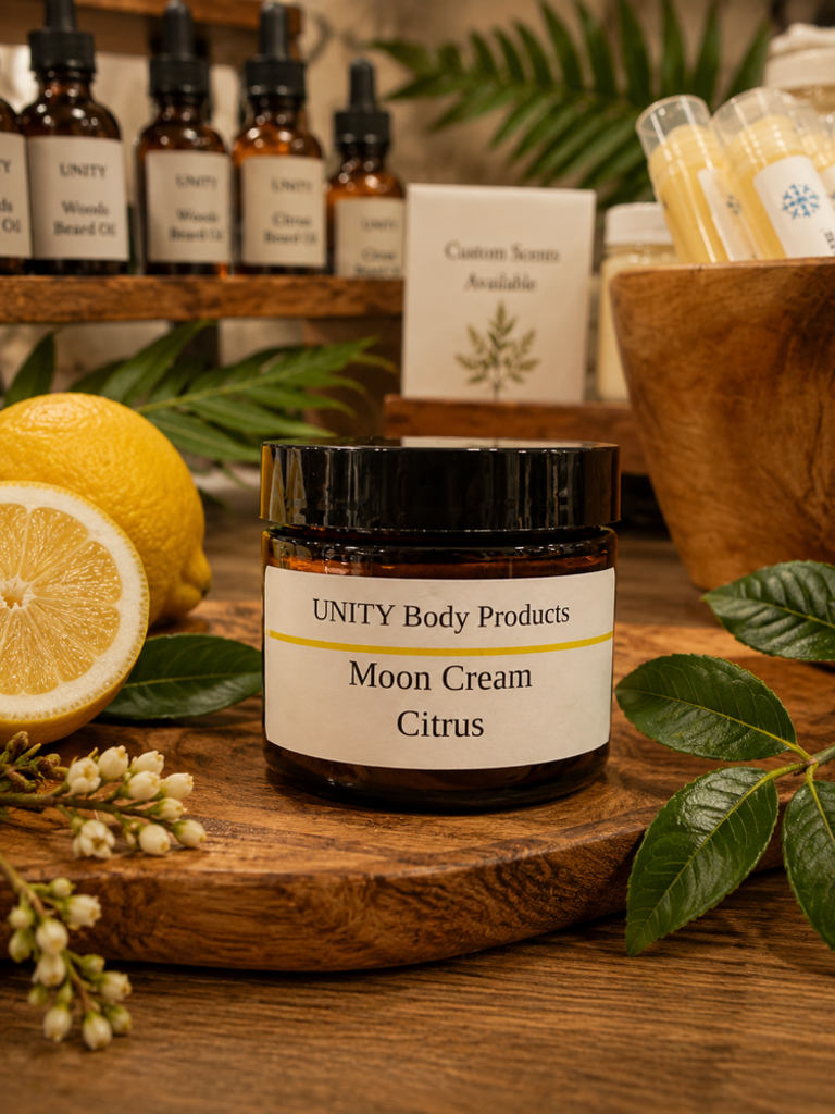 Jar of Moon Cream Citrus on wooden surface with lemons, leaves, and bottles in background.