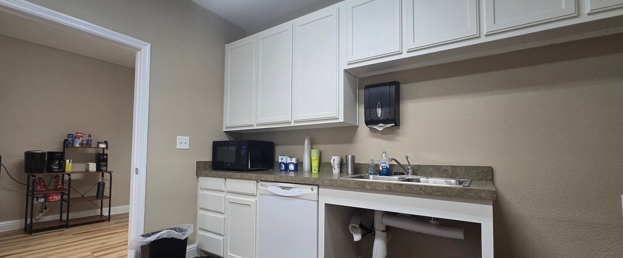 Kitchen with white cabinets, countertop, sink, and a wall-mounted paper towel dispenser.