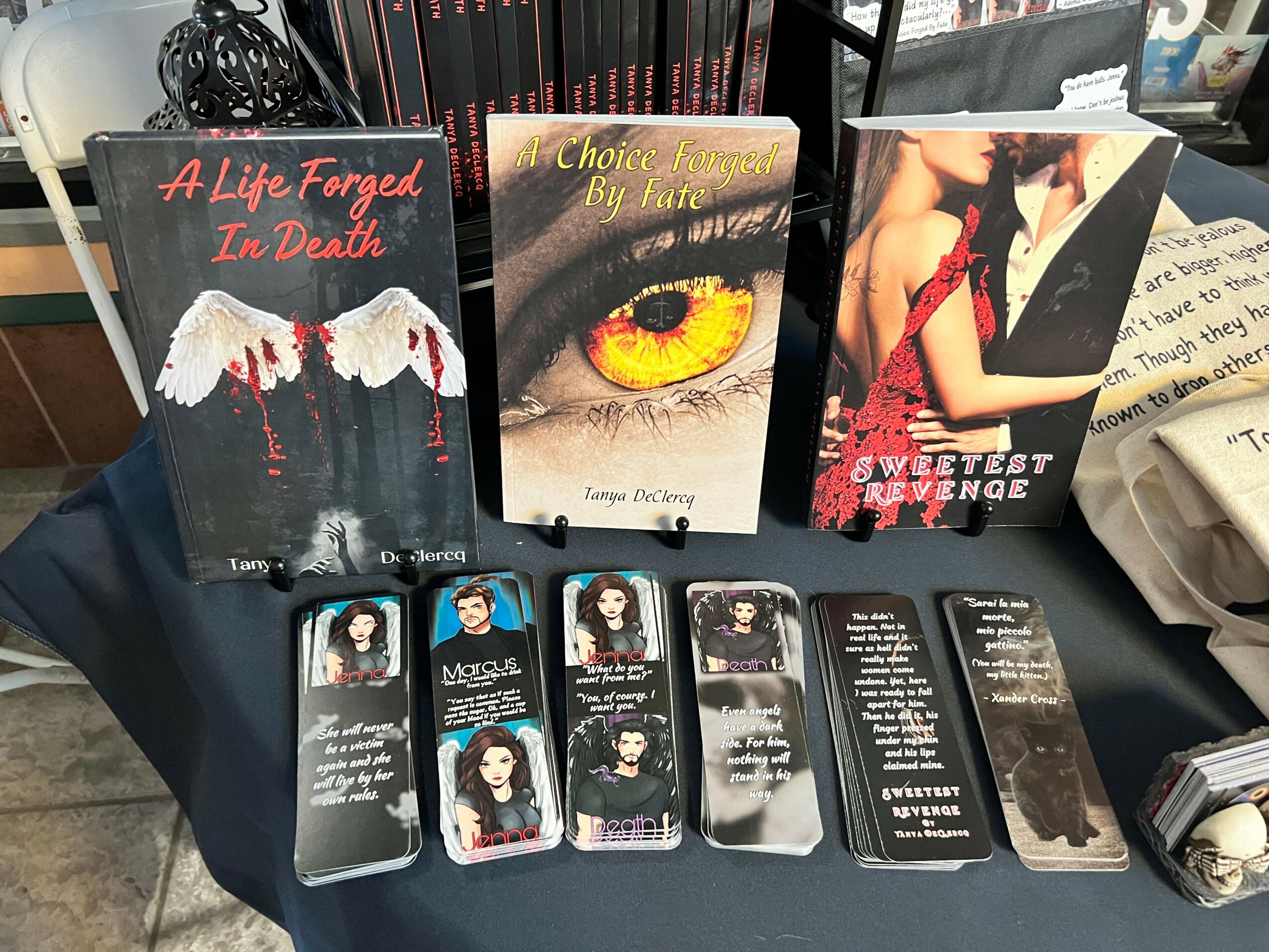 Three books displayed on a table with various bookmarks and papers, focusing on dark-themed covers and titles.