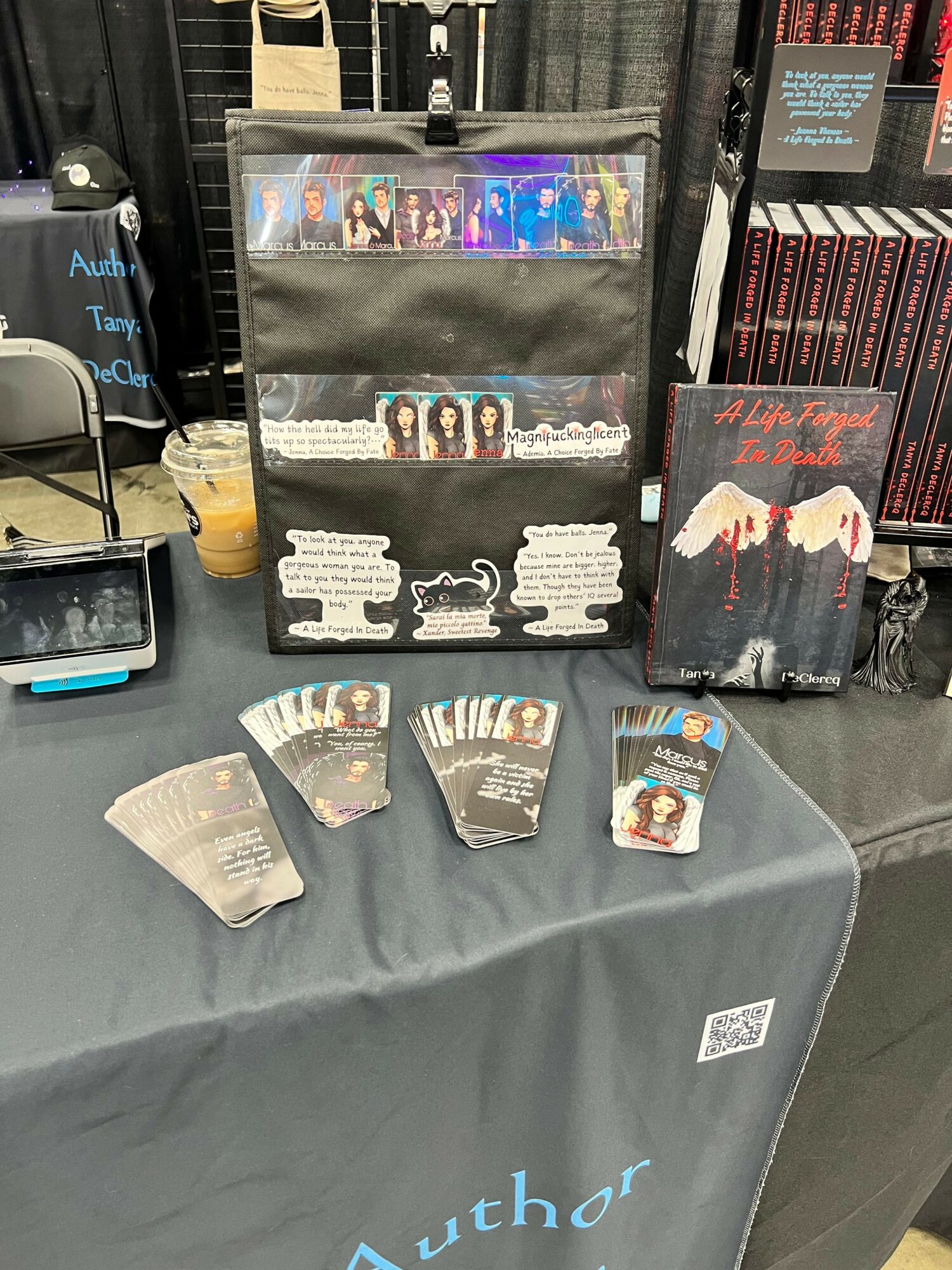 Display of DVDs and promotional materials on a table, with a gray tablecloth and books in the background.