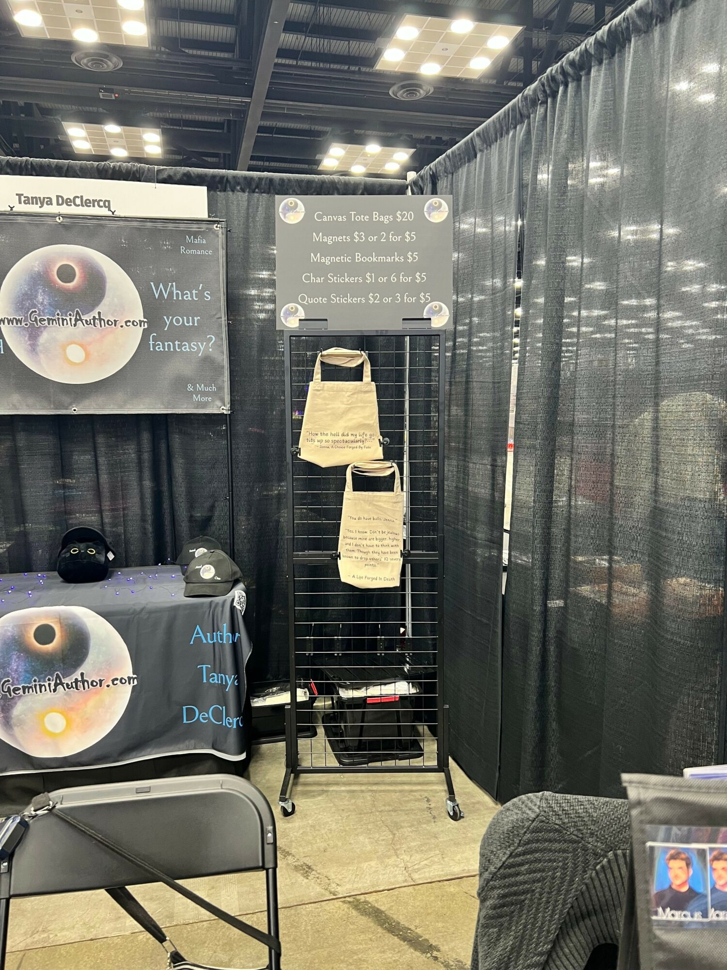 Black display board with white text, a beige bag hanging, and a black and white poster with a circular design, in an indoor setting.