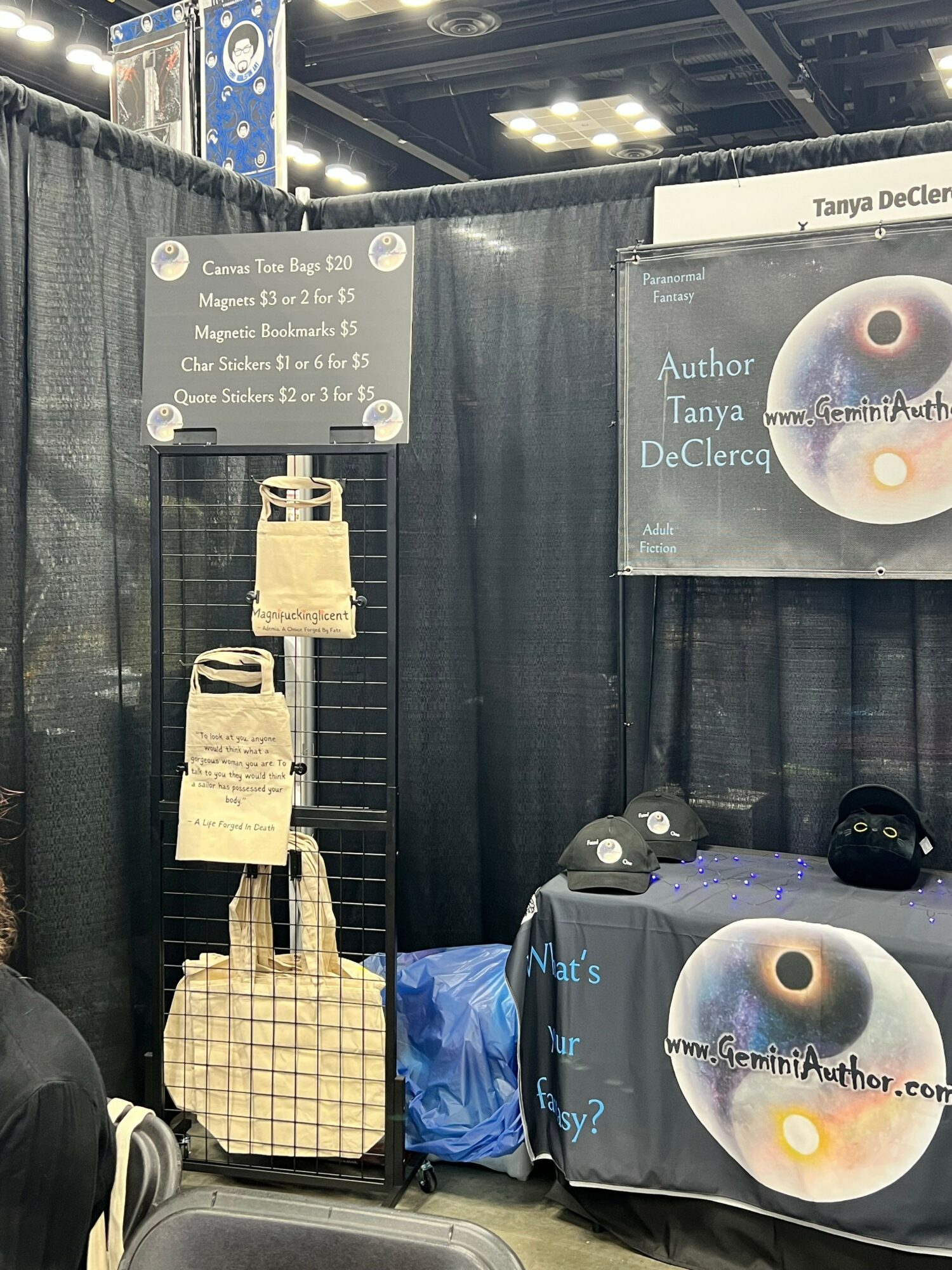 Black booth with posters and display items, including a sign with text and a model of a lighthouse, at an event.