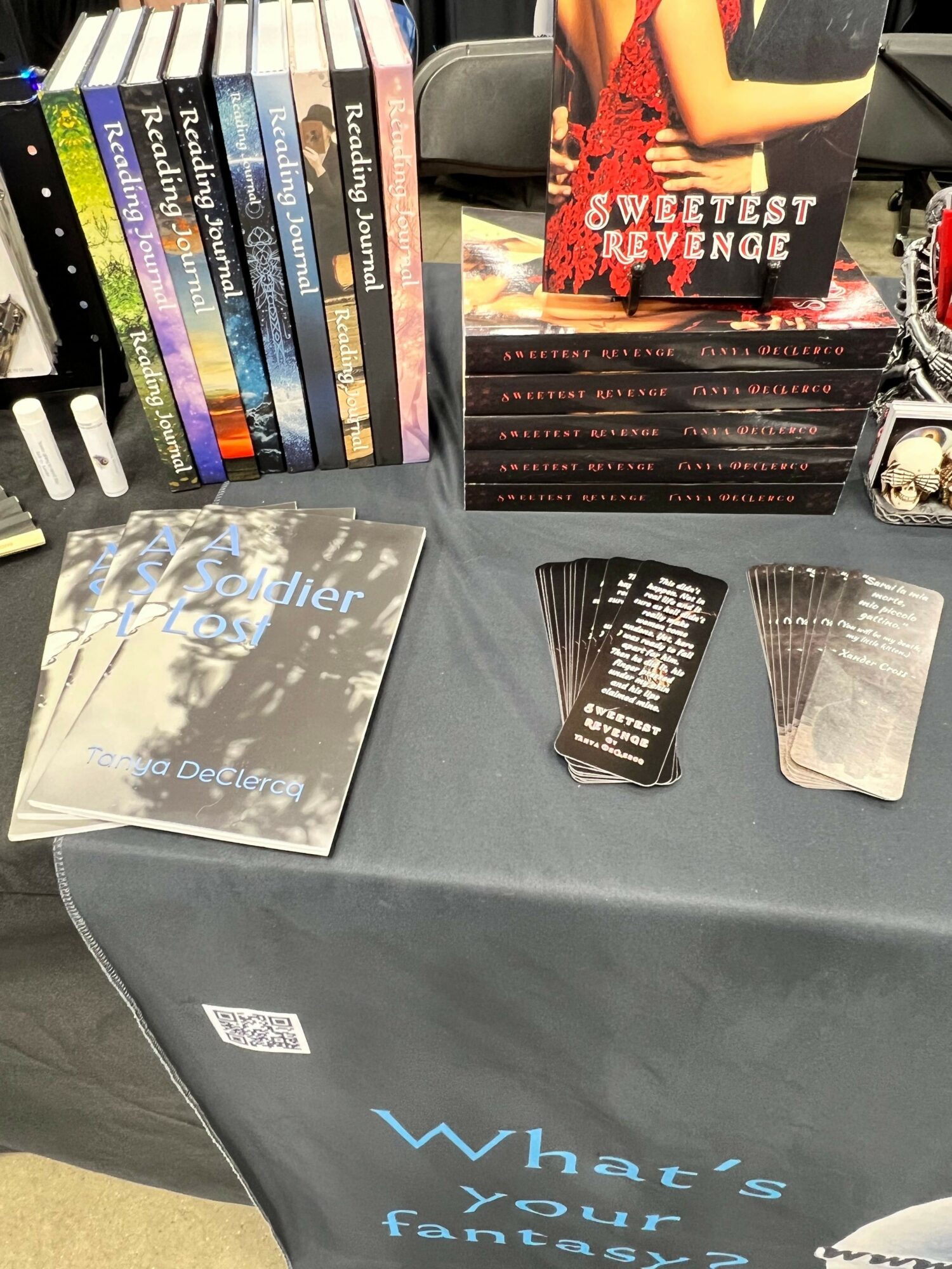 Table with books, magazines, and promotional materials, including a magazine with a woman on the cover and a book titled 'The Winter'.