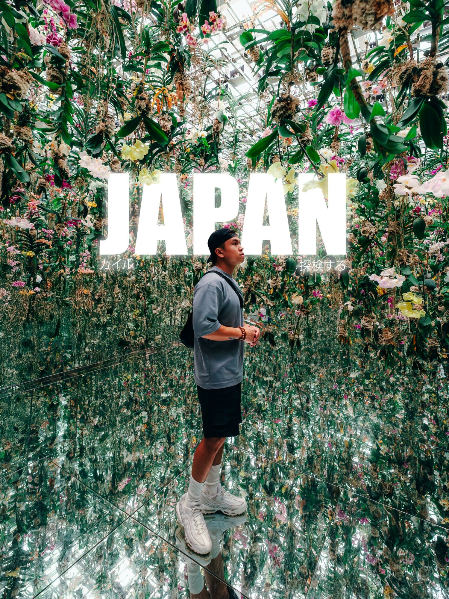 Person standing in a vibrant floral indoor garden with large white text reading 'JAPAN' behind them.