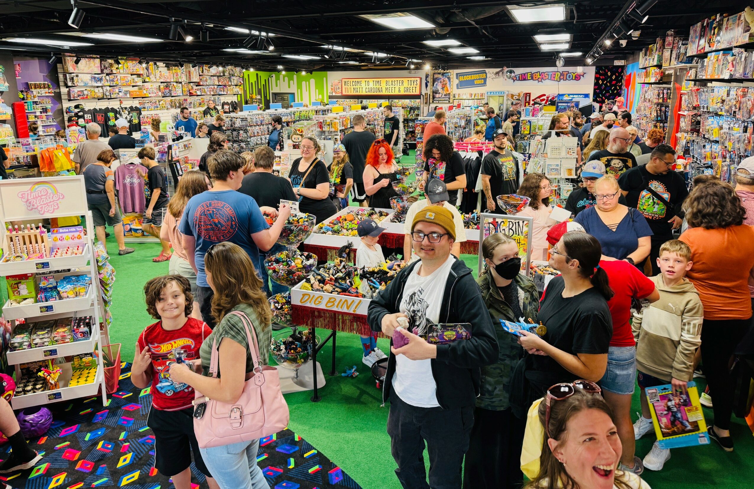 Crowded toy store with children and adults shopping, colorful shelves, and bright lighting.