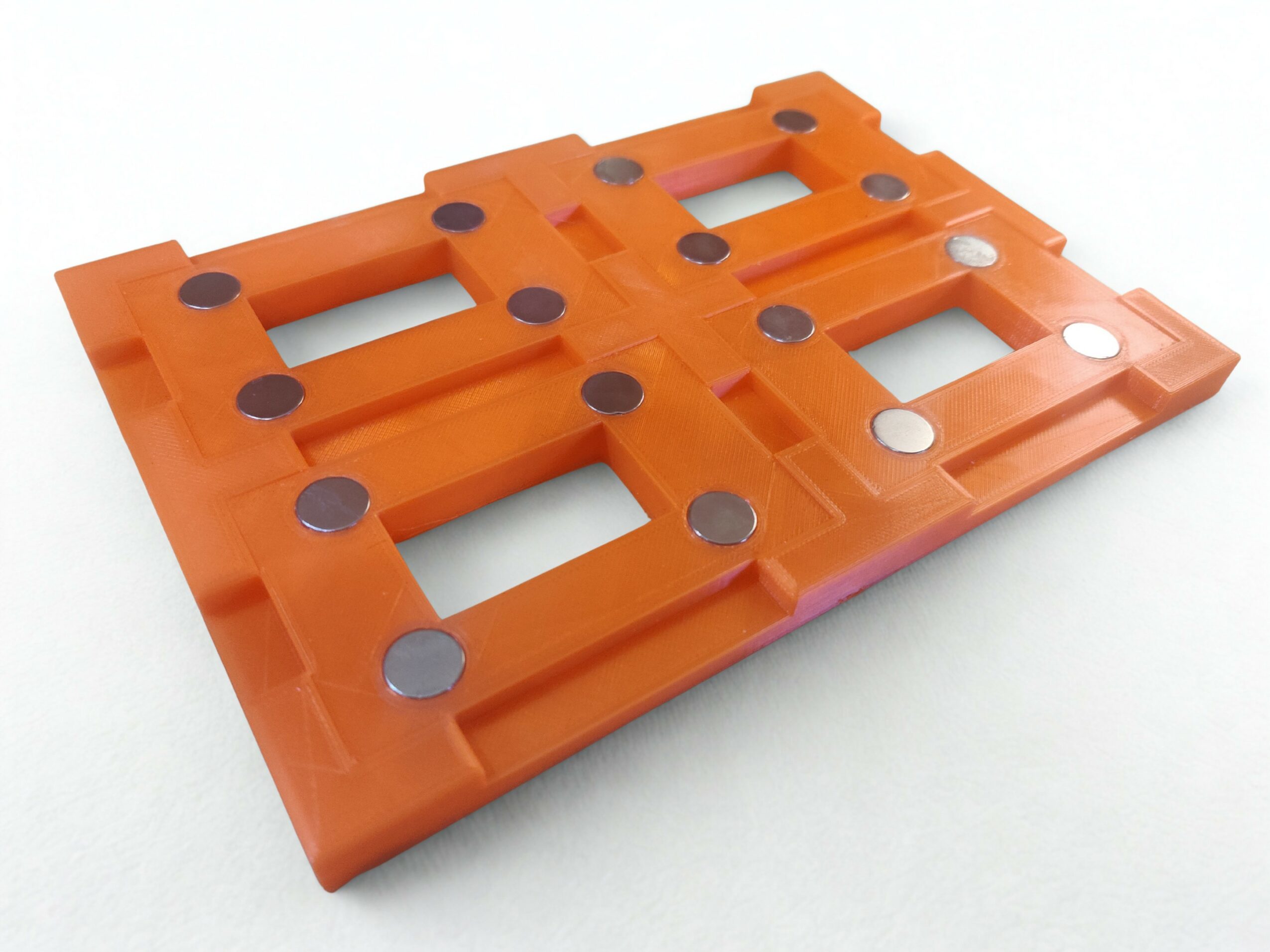 Orange plastic pallet with black and silver circular pads, viewed from above, on a white background.