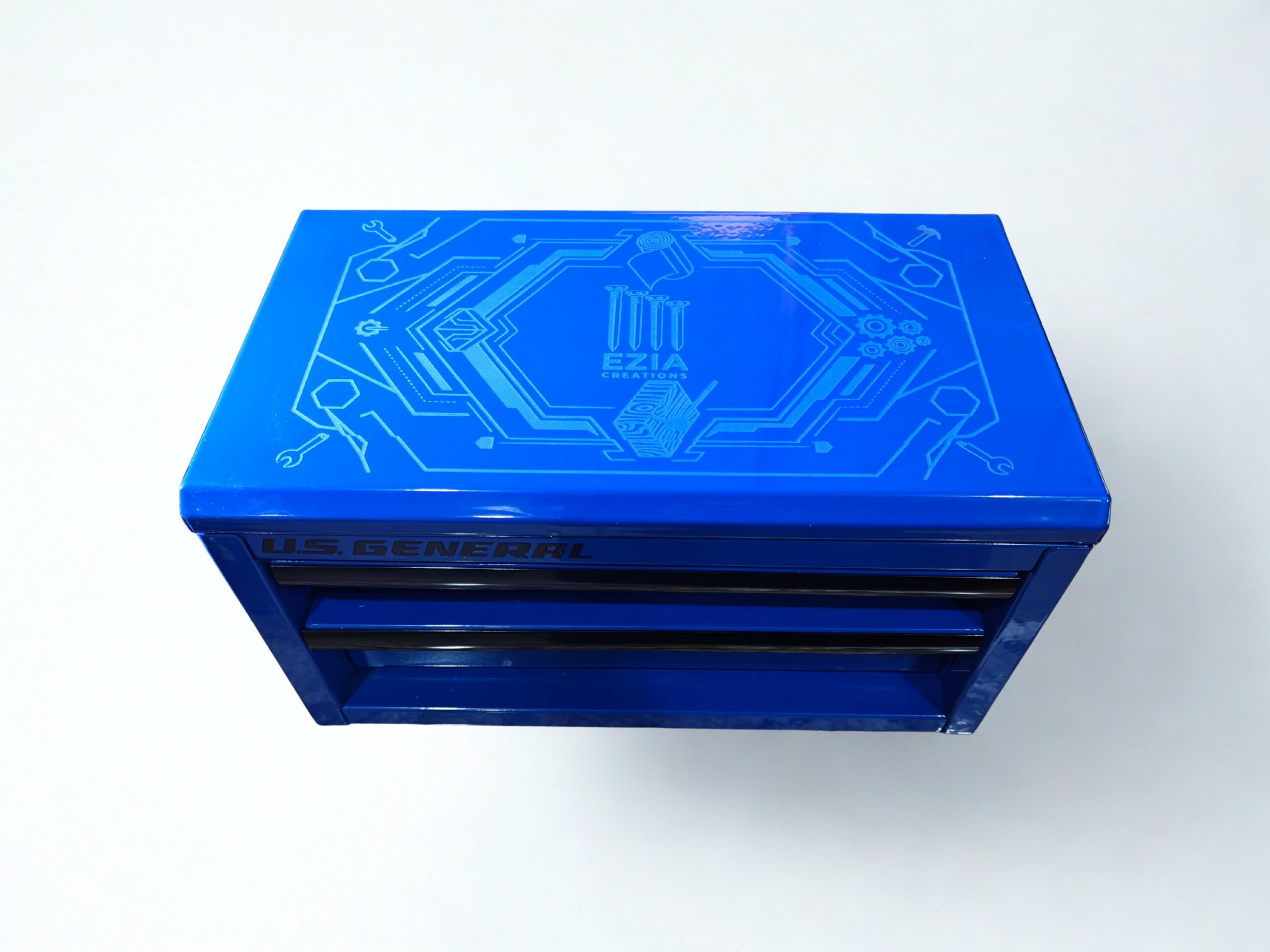 Blue rectangular electronic device with circuit board design on top, placed on a white surface.